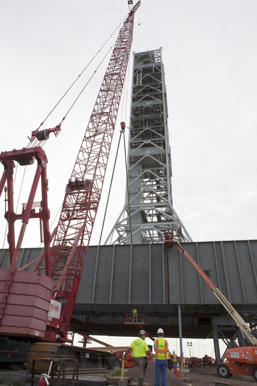 CAPE CANAVERAL, Fla. – A crane is used to move the final large steel beam into position for installation on the base of the Mobile Launcher, or ML, at the Mobile Launcher Park Site at NASA's Kennedy Space Center in Florida. Construction workers on lifts monitor the progress to begin attaching the final large beam to the ML structure. The ML is being modified and strengthened to accommodate the weight, size and thrust at launch of NASA's Space Launch System, or SLS, and Orion spacecraft.    In 2013, the agency awarded a contract to J.P. Donovan Construction Inc. of Rockledge, Fla., to modify the ML, which is one of the key elements of ground support equipment that is being upgraded by the Ground Systems Development and Operations Program at Kennedy. The existing 24-foot exhaust hole is being enlarged and strengthened for the larger, heavier SLS rocket. The ML will carry the SLS rocket and Orion spacecraft to Launch Pad 39B for its first uncrewed mission, Exploration Mission-1, in 2018. Photo credit: NASA/Daniel Casper