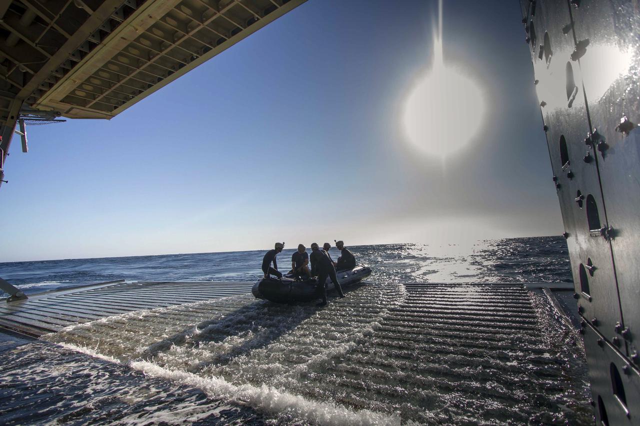 SAN DIEGO, Calif. – A Zodiac boat containing U.S. Navy divers is positioned at the entrance to the well deck of the USS Anchorage on the third day of Orion Underway Recovery Test 3 in the Pacific Ocean.    NASA, Lockheed Martin and U.S. Navy personnel are conducting the recovery test using the test vehicle to prepare for recovery of the Orion crew module on its return from a deep space mission. The test allows the teams to demonstrate and evaluate the recovery processes, procedures, hardware and personnel in open waters. The Ground Systems Development and Operations Program is conducting the underway recovery tests. Orion is the exploration spacecraft designed to carry astronauts to destinations not yet explored by humans, including an asteroid and Mars. It will have emergency abort capability, sustain the crew during space travel and provide safe re-entry from deep space return velocities. The first unpiloted test flight of Orion is scheduled to launch in 2014 atop a United Launch Alliance Delta IV Heavy rocket and in 2018 on NASA’s Space Launch System rocket. For more information, visit http://www.nasa.gov/orion. Photo credit: NASA/Cory Huston