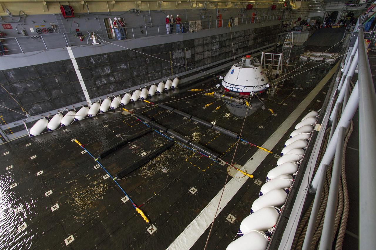 SAN DIEGO, Calif. – The Orion boilerplate test vehicle is tethered in the water-filled well deck of the USS Anchorage during the Underway Recovery Test 3 mission simulation day in the Pacific Ocean.     NASA, Lockheed Martin and U.S. Navy personnel are conducting the recovery test using the test vehicle to prepare for recovery of the Orion crew module on its return from a deep space mission. The test allows the teams to demonstrate and evaluate the recovery processes, procedures, hardware and personnel in open waters. The Ground Systems Development and Operations Program is conducting the underway recovery tests. Orion is the exploration spacecraft designed to carry astronauts to destinations not yet explored by humans, including an asteroid and Mars. It will have emergency abort capability, sustain the crew during space travel and provide safe re-entry from deep space return velocities. The first unpiloted test flight of Orion is scheduled to launch in 2014 atop a United Launch Alliance Delta IV Heavy rocket and in 2018 on NASA’s Space Launch System rocket. For more information, visit http://www.nasa.gov/orion. Photo credit: NASA/Cory Huston