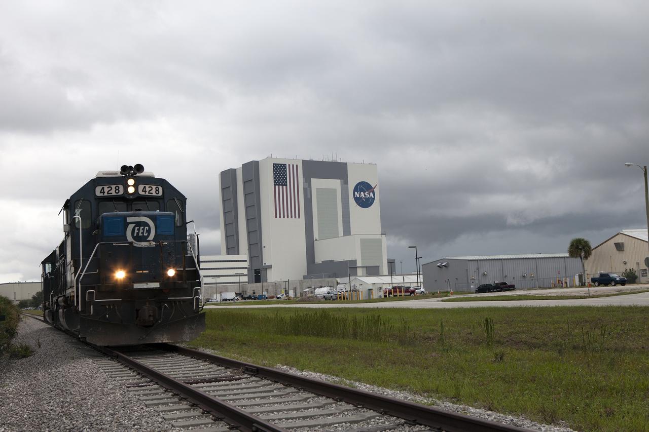 CAPE CANAVERAL, Fla. – Coupled Florida East Coast Railway, or FEC, locomotives No. 433 and No. 428 pass the Vehicle Assembly Building in Launch Complex 39 at NASA’s Kennedy Space Center in Florida on their way to NASA's Locomotive Maintenance Facility. Kennedy's Center Planning and Development Directorate has enlisted the locomotives to support a Rail Vibration Test for the Canaveral Port Authority.    The purpose of the test is to collect amplitude, frequency and vibration test data utilizing two Florida East Coast locomotives operating on KSC tracks to ensure that future railroad operations will not affect launch vehicle processing at the center. Buildings instrumented for the test include the Rotation Processing Surge Facility, Thermal Protection Systems Facility, Vehicle Assembly Building, Orbiter Processing Facility and Booster Fabrication Facility. Photo credit: NASA/Daniel Casper