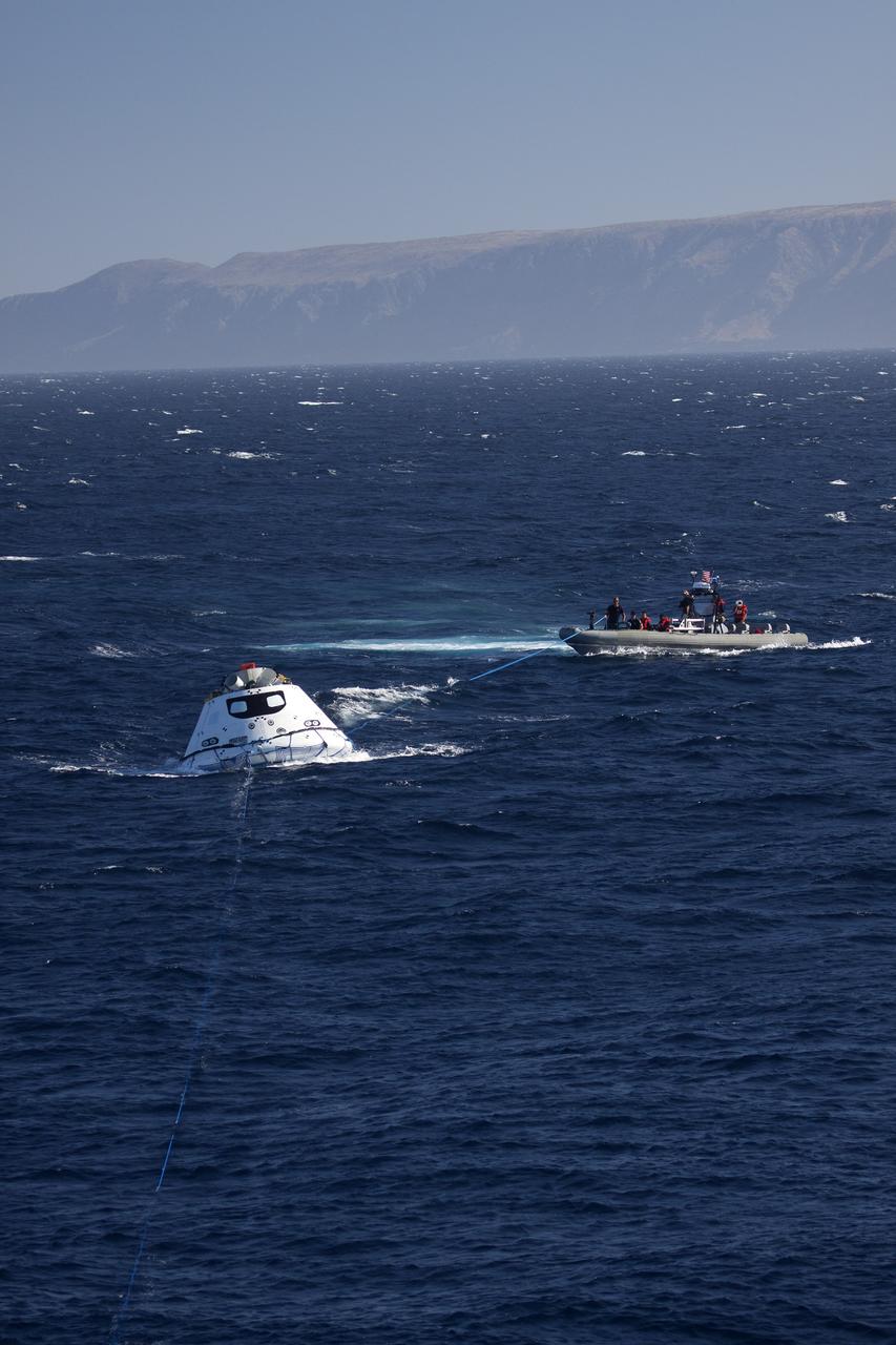 SAN DIEGO, Calif. – The Orion boilerplate test vehicle floats in the Pacific Ocean near the USS Anchorage during Underway Recovery Test 3. Tether lines have been attached to the test vehicle. Nearby, recovery team members in a rigid hull inflatable boat are practicing recovery procedures. NASA, Lockheed Martin and U.S. Navy personnel are conducting the recovery test to prepare for recovery of the Orion crew module on its return from a deep space mission. The test allows the teams to demonstrate and evaluate the recovery processes, procedures, hardware and personnel in open waters.    The Ground Systems Development and Operations Program is conducting the underway recovery tests. Orion is the exploration spacecraft designed to carry astronauts to destinations not yet explored by humans, including an asteroid and Mars. It will have emergency abort capability, sustain the crew during space travel and provide safe re-entry from deep space return velocities. The first unpiloted test flight of Orion is scheduled to launch in 2014 atop a United Launch Alliance Delta IV Heavy rocket and in 2018 on NASA’s Space Launch System rocket. For more information, visit http://www.nasa.gov/orion. Photo credit: NASA/Cory Huston