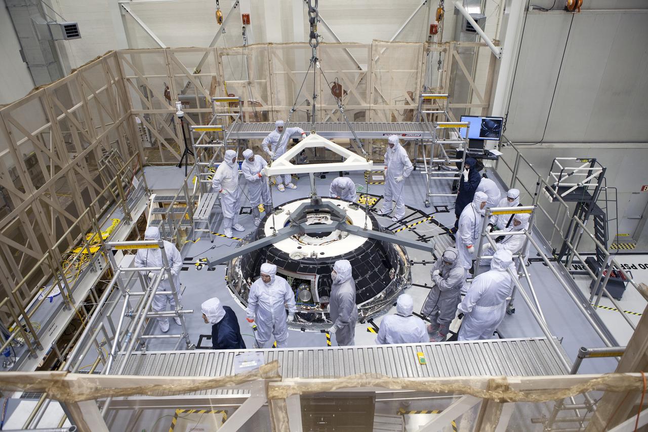 CAPE CANAVERAL, Fla. – Inside the Neil Armstrong Operations and Checkout Building high bay at NASA’s Kennedy Space Center in Florida, Lockheed Martin technicians on a work platform monitor the progress as a crane lowers the forward bay cover onto the Orion crew module for a fit check. The cover is a shell that fits over Orion's crew module to protect the spacecraft during launch, orbital flight and re-entry into Earth's atmosphere. When Orion returns from space, the cover must be jettisoned high above the ground so that the parachutes can deploy and unfurl. Orion is the exploration spacecraft designed to carry astronauts to destinations not yet explored by humans, including an asteroid and Mars. It will have emergency abort capability, sustain the crew during space travel and provide safe re-entry from deep space return velocities. The first unpiloted flight test of Orion is scheduled to launch in December 2014 atop a United Launch Alliance Delta IV Heavy rocket and in 2018 on NASA’s Space Launch System rocket. For more information, visit http://www.nasa.gov/orion. Photo credit: NASA/Daniel Casper
