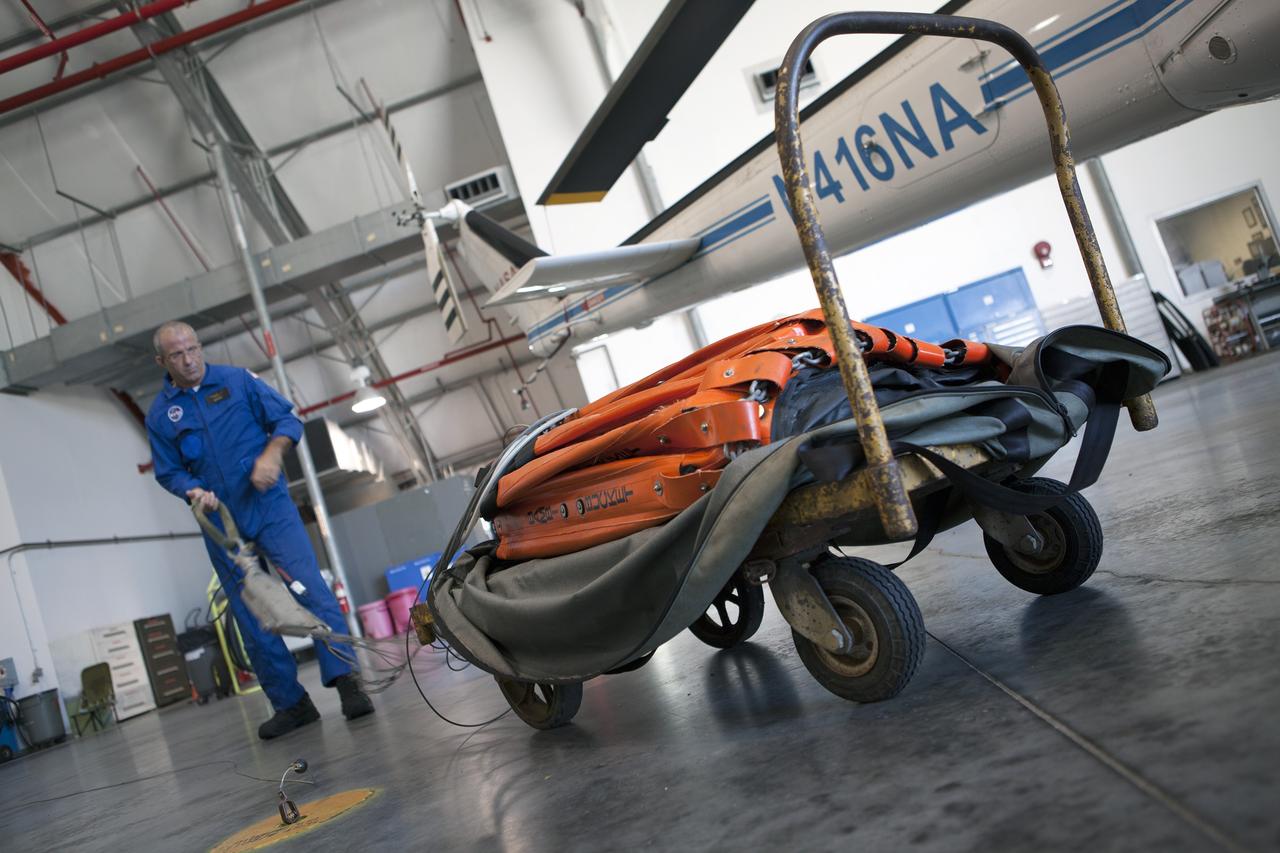 CAPE CANAVERAL, Fla. -- At NASA's Kennedy Space Center in Florida, helicopter crew chief Mark Smith, of URS Federal Technical Services Inc., checks out a Bambi Bucket prior to a training exercise to practice firefighting techniques. A three-person helicopter crew recently practiced using a Bambi Bucket to pick up water from a nearby waterway and dropping it on simulated targets at the center’s Shuttle Landing Facility.      Firefighters respond to wildfires with teams on the ground and in the air. The most up-to-date tools include helicopters that use Bambi Buckets large quantities of water. NASA Flight Operations teams are training to perfect the skills needed to ensure they are ready to use tools, such as the Bambi Bucket, in the event of an out-of-control blaze at the spaceport. Photo credit: NASA/Frankie Martin