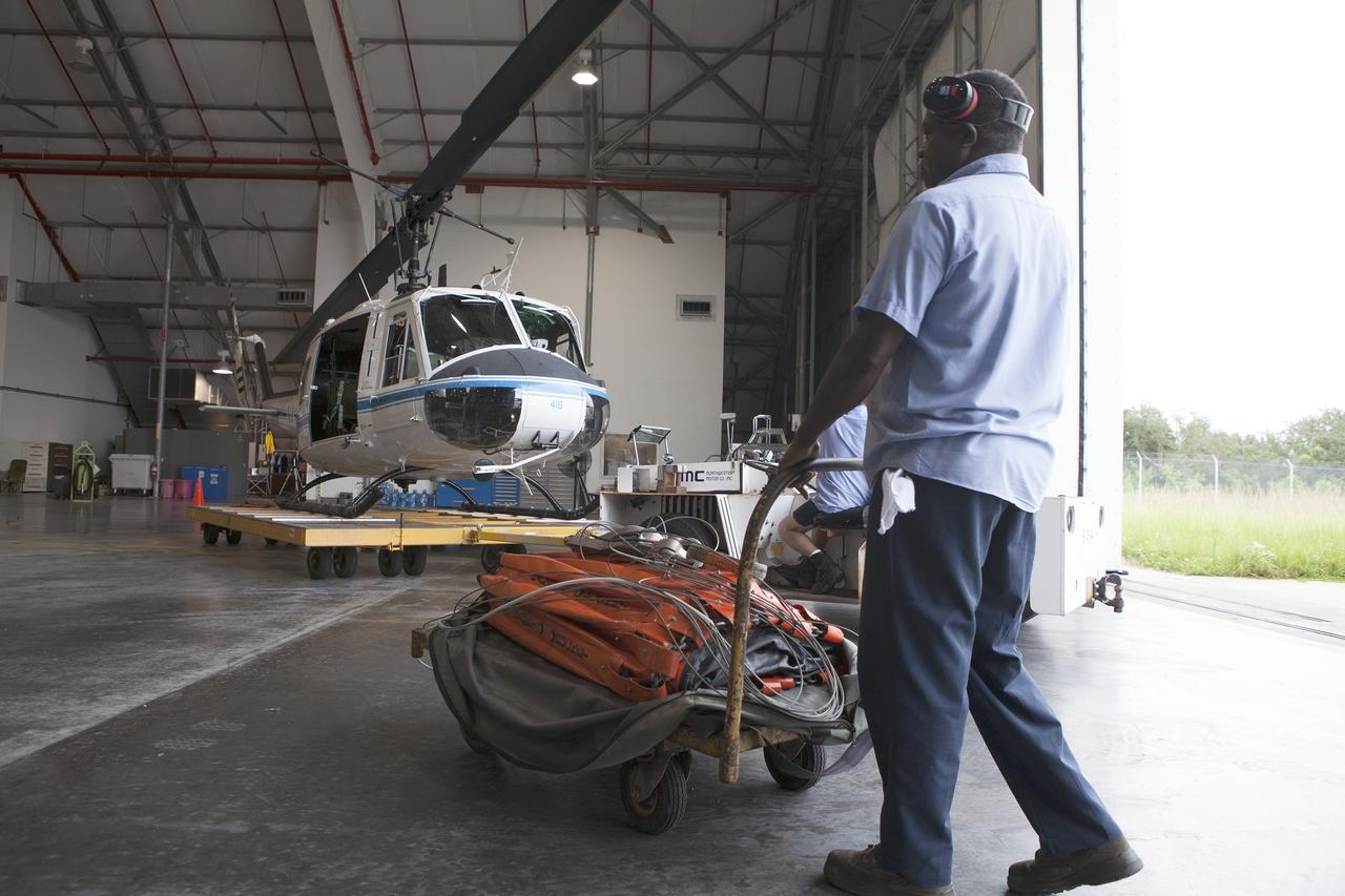CAPE CANAVERAL, Fla. -- At NASA's Kennedy Space Center in Florida, John Miller of URS Federal Technical Services moves a Bambi Bucket and its associated cables are moved outside the Shuttle Landing Facility hangar prior to a training exercise to practice firefighting techniques. A three-person helicopter crew recently practiced using a Bambi Bucket to pick up water from a nearby waterway and dropping it on simulated targets at the center’s Shuttle Landing Facility.        Firefighters respond to wildfires with teams on the ground and in the air. The most up-to-date tools include helicopters that use Bambi Buckets large quantities of water. NASA Flight Operations teams are training to perfect the skills needed to ensure they are ready to use tools, such as the Bambi Bucket, in the event of an out-of-control blaze at the spaceport. Photo credit: NASA/Frankie Martin