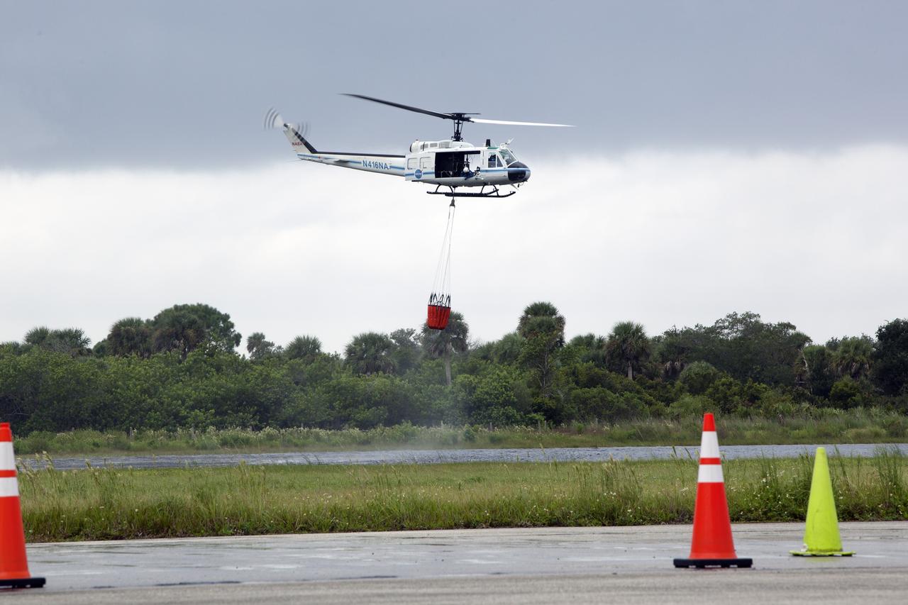 CAPE CANAVERAL, Fla. -- At NASA's Kennedy Space Center in Florida, the crew of the NASA helicopter carefully lifts a Bambi Bucket from a canal near the Shuttle Landing Facility. Minutes later, the water was dropped on the target cones in the foreground, using techniques that would be employed to fight a brush fire at the Kennedy Space Center. Firefighters respond to wildfires with teams on the ground and in the air. The most up-to-date tools include helicopters that use Bambi Buckets large quantities of water. NASA Flight Operations teams are training to perfect the skills needed to ensure they are ready to use tools, such as the Bambi Bucket, in the event of an out-of-control blaze at the spaceport. Photo credit: NASA/Frankie Martin