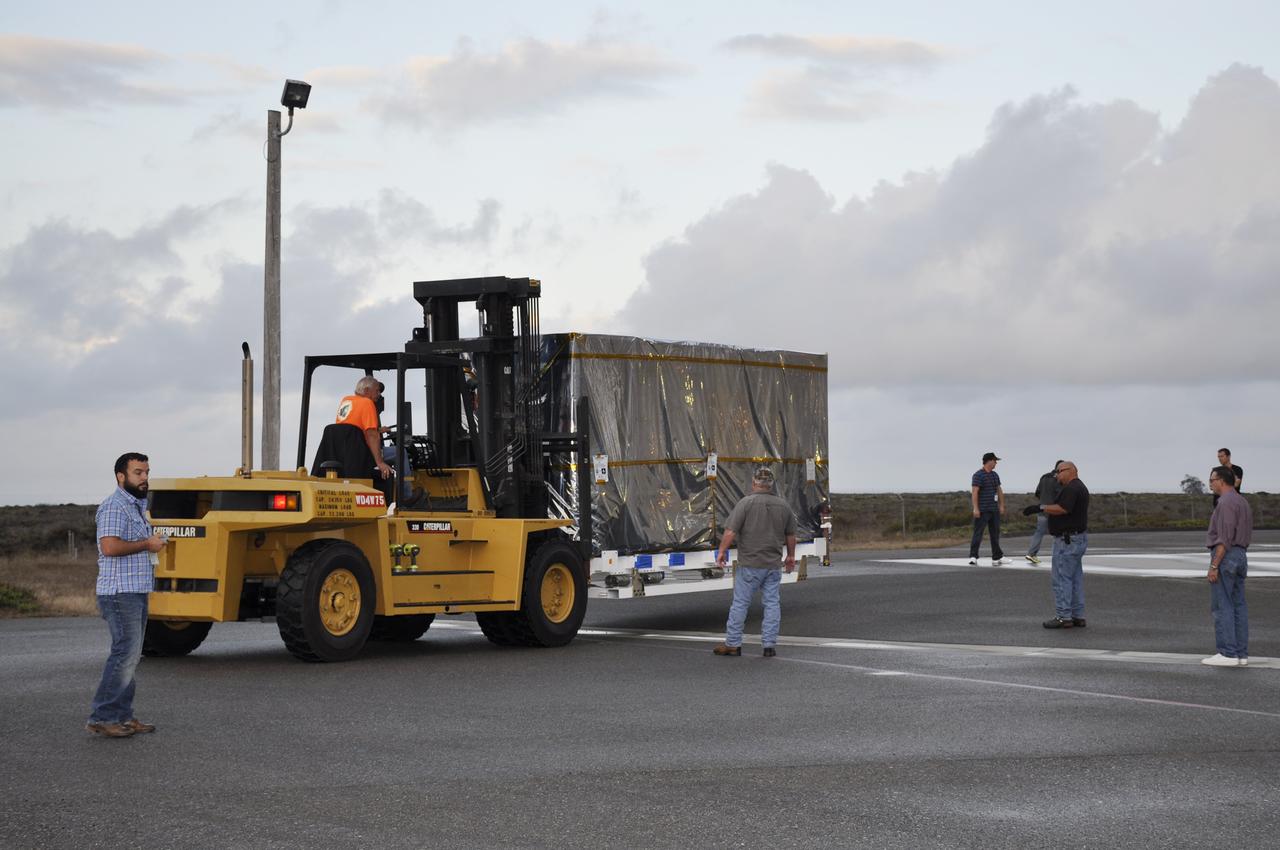 VANDENBERG AIR FORCE BASE, Calif. – Workers push the pallet supporting the transportation container protecting NASA's Soil Moisture Active Passive, or SMAP, spacecraft into the Astrotech payload processing facility on Vandenberg Air Force Base in California. SMAP will launch on a Delta II 7320 configuration vehicle featuring a United Launch Alliance first stage booster powered by an Aerojet Rocketdyne RS-27A main engine and three Alliant Techsystems, or ATK, strap-on solid rocket motors. Once on station in Earth orbit, SMAP will provide global measurements of soil moisture and its freeze/thaw state. These measurements will be used to enhance understanding of processes that link the water, energy and carbon cycles, and to extend the capabilities of weather and climate prediction models. SMAP data also will be used to quantify net carbon flux in boreal landscapes and to develop improved flood prediction and drought monitoring capabilities. Launch from Space Launch Complex 2 is targeted for Jan. 29, 2015. To learn more about SMAP, visit http://smap.jpl.nasa.gov. Photo credit: NASA/Randy Beaudoin