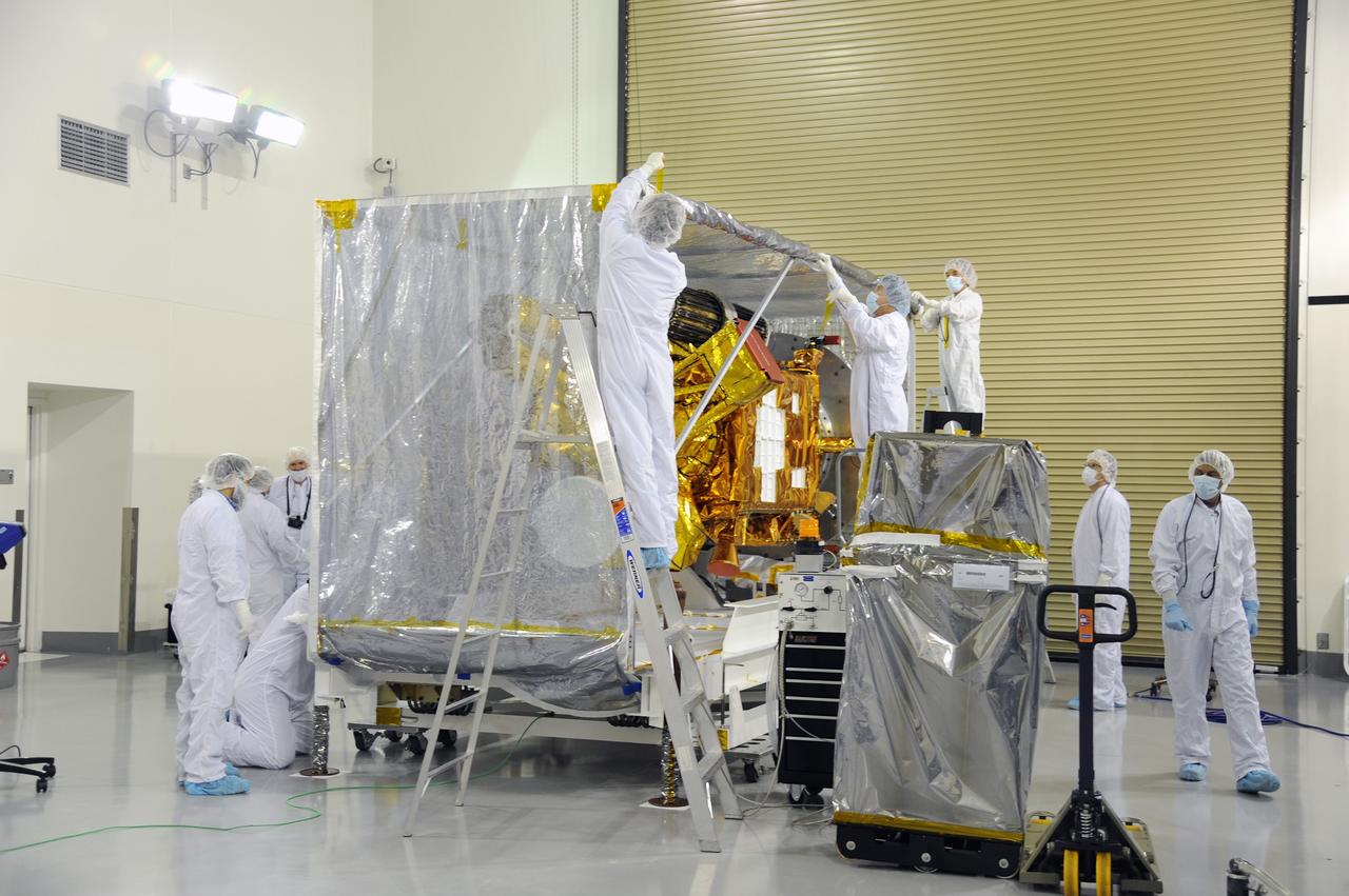 VANDENBERG AIR FORCE BASE, Calif. – Workers remove the protective covering from around NASA's Soil Moisture Active Passive, or SMAP, spacecraft in the Astrotech payload processing facility on Vandenberg Air Force Base in California during a post-shipment inspection. The covering protected the spacecraft from static-charge buildup and contamination while it was in transit from NASA's Jet Propulsion Laboratory in Pasadena, California.    SMAP will launch on a Delta II 7320 configuration vehicle featuring a United Launch Alliance first stage booster powered by an Aerojet Rocketdyne RS-27A main engine and three Alliant Techsystems, or ATK, strap-on solid rocket motors. Once on station in Earth orbit, SMAP will provide global measurements of soil moisture and its freeze/thaw state. These measurements will be used to enhance understanding of processes that link the water, energy and carbon cycles, and to extend the capabilities of weather and climate prediction models. SMAP data also will be used to quantify net carbon flux in boreal landscapes and to develop improved flood prediction and drought monitoring capabilities. Launch from Space Launch Complex 2 is targeted for Jan. 29, 2015. To learn more about SMAP, visit http://smap.jpl.nasa.gov.  Photo credit: NASA/Robert Rasmison