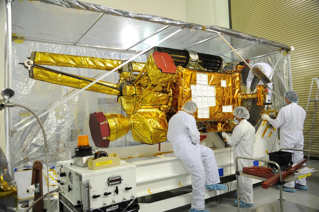 VANDENBERG AIR FORCE BASE, Calif. – Workers inspect NASA's Soil Moisture Active Passive, or SMAP, spacecraft after its protective covering is removed in the Astrotech payload processing facility on Vandenberg Air Force Base in California during a post-shipment inspection. The covering protected the spacecraft from static-charge buildup and contamination while it was in transit from NASA's Jet Propulsion Laboratory in Pasadena, California.    SMAP will launch on a Delta II 7320 configuration vehicle featuring a United Launch Alliance first stage booster powered by an Aerojet Rocketdyne RS-27A main engine and three Alliant Techsystems, or ATK, strap-on solid rocket motors. Once on station in Earth orbit, SMAP will provide global measurements of soil moisture and its freeze/thaw state. These measurements will be used to enhance understanding of processes that link the water, energy and carbon cycles, and to extend the capabilities of weather and climate prediction models. SMAP data also will be used to quantify net carbon flux in boreal landscapes and to develop improved flood prediction and drought monitoring capabilities. Launch from Space Launch Complex 2 is targeted for Jan. 29, 2015. To learn more about SMAP, visit http://smap.jpl.nasa.gov.  Photo credit: NASA/Robert Rasmison