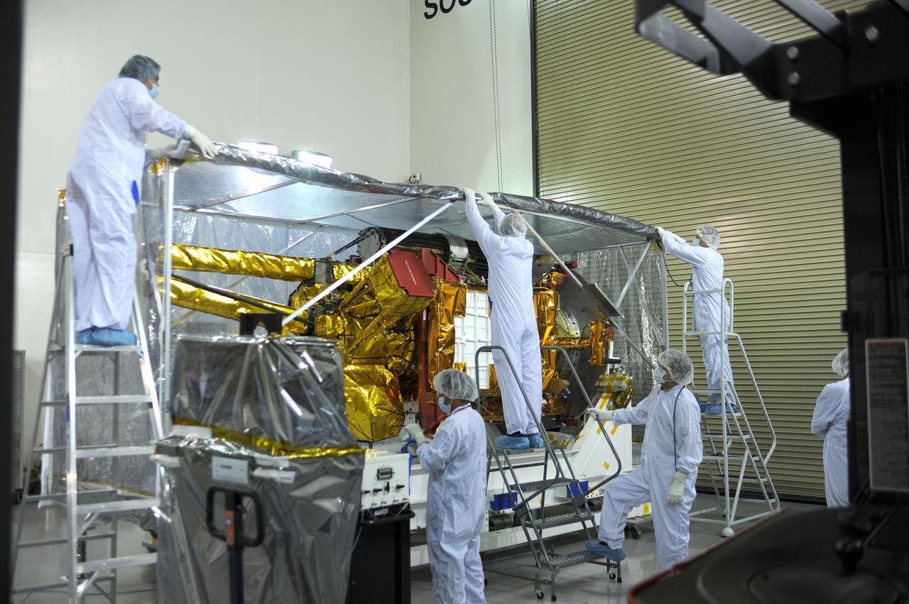 VANDENBERG AIR FORCE BASE, Calif. – Inside the Astrotech payload processing facility on Vandenberg Air Force Base in California, engineers and technicians remove a protective covering from NASA's Soil Moisture Active Passive, or SMAP, spacecraft.    SMAP will launch on a Delta II 7320 configuration vehicle featuring a United Launch Alliance first stage booster powered by an Aerojet Rocketdyne RS-27A main engine and three Alliant Techsystems, or ATK, strap-on solid rocket motors. Once on station in Earth orbit, SMAP will provide global measurements of soil moisture and its freeze/thaw state. These measurements will be used to enhance understanding of processes that link the water, energy and carbon cycles, and to extend the capabilities of weather and climate prediction models. SMAP data also will be used to quantify net carbon flux in boreal landscapes and to develop improved flood prediction and drought monitoring capabilities. Launch from Space Launch Complex 2 is targeted for Jan. 29, 2015. To learn more about SMAP, visit http://smap.jpl.nasa.gov Photo credit: NASA/ Robert Rasmison