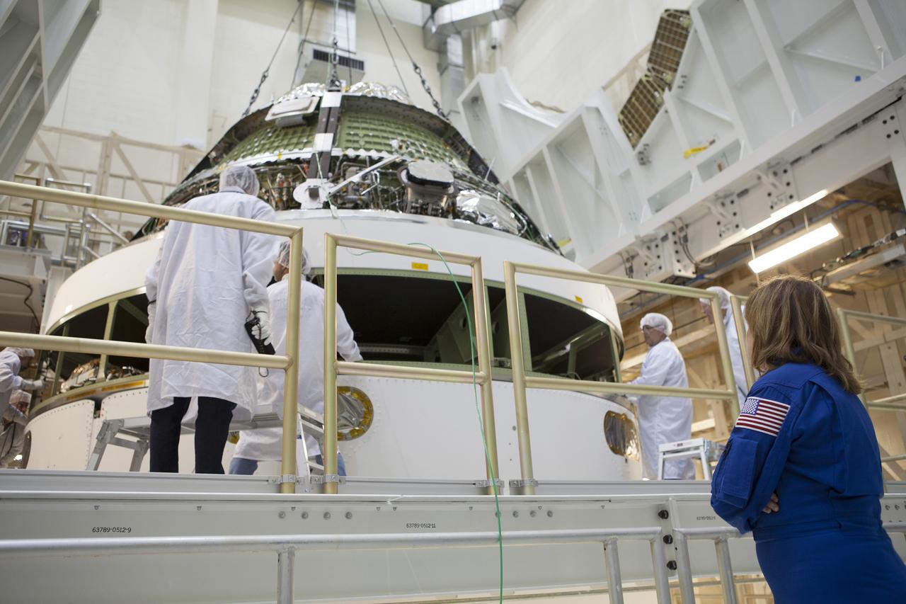 CAPE CANAVERAL, Fla. – Inside the Operations and Checkout Building high bay at NASA's Kennedy Space Center in Florida, Lockheed Martin technicians monitor the progress as a crane lowers the Orion crew module for stacking on the service module. The modules will be mated and then put through their final system tests before they are transported to the Payload Hazardous Servicing Facility for fueling. In the foreground, observing the processing, is NASA astronaut Anna Fisher.     Orion is the exploration spacecraft designed to carry astronauts to destinations not yet explored by humans, including an asteroid and Mars. It will have emergency abort capability, sustain the crew during space travel and provide safe re-entry from deep space return velocities. Orion's first flight test is scheduled to launch in December atop a Delta IV Heavy rocket from Cape Canaveral Air Force Station in Florida to an altitude of 3,600 miles above the Earth's surface. The two-orbit, four-hour flight test will help engineers evaluate the systems critical to crew safety including the heat shield, parachute system and launch abort system. For more information, visit http://www.nasa.gov/orion. Photo credit: NASA/Dimitri Gerondidakis