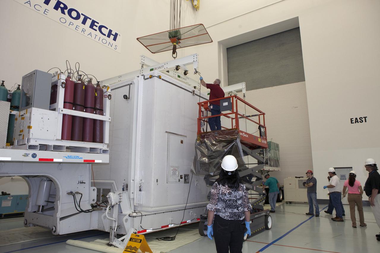 CAPE CANAVERAL, Fla. – Workers attach a crane to the protective shipping container to prepare to uncover the lower stack, mini-stack number 1, two of the observatories for NASA's Magnetospheric Multiscale Observatory, or MMS. They were delivered to the Building 2 south encapsulation bay at the Astrotech payload processing facility in Titusville, Florida, near Kennedy Space Center.    The MMS upper stack, mini-stack number 2, is scheduled to arrive in about two weeks.  MMS is a Solar Terrestrial Probes mission comprising four identically instrumented spacecraft that will use Earth’s magnetosphere as a laboratory to study the microphysics of three fundamental plasma processes: magnetic reconnection, energetic particle acceleration and turbulence.  Launch aboard a United Launch Alliance Atlas V rocket from Space Launch Complex 41 on Cape Canaveral Air Force Station is targeted for March 12, 2015. To learn more about MMS, visit http://mms.gsfc.nasa.gov.  Photo credit: NASA/Dan Casper