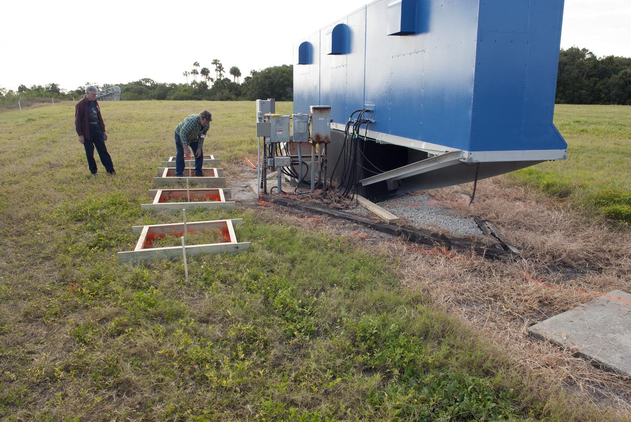 CAPE CANAVERAL, Fla. -- At NASA's Kennedy Space Center in Florida, Jeff Pratt and Frank Morse with Abacus Technology prep the area behind the current countdown clock for the groundbreaking ceremony for the new countdown clock. The old timepiece was designed by Kennedy engineers and built by Kennedy technicians in 1969. Not including the triangular concrete and aluminum base, the famous landmark is nearly 6 feet 70 inches high, 26 feet 315 inches wide and 3 feet deep. The new display will be similar in size, with the screen being nearly 26 feet wide by 7 feet high. For more information on the countdown clock, go to http://go.nasa.gov/10Zku10. Photo credit: NASA/Jim Grossmann