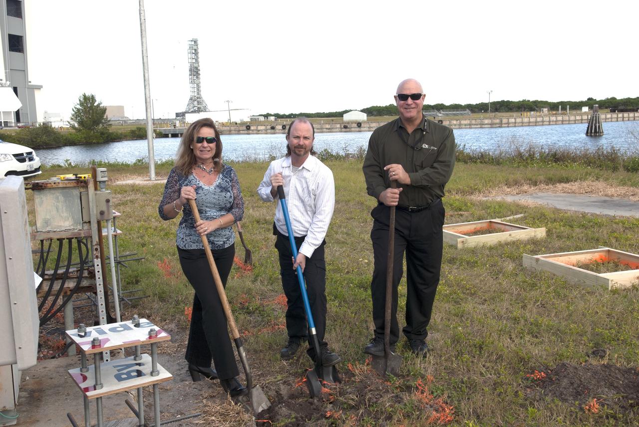 CAPE CANAVERAL, Fla. -- At NASA's Kennedy Space Center in Florida, Project Manager Sonja Hernandez, Kennedy TV senior systems engineer Ronald Gonser and Kennedy/IMCS senior manager Jeff Van Pelt dig in behind the current countdown clock during the groundbreaking ceremony for the new countdown clock. The old timepiece was designed by Kennedy engineers and built by Kennedy technicians in 1969. Not including the triangular concrete and aluminum base, the famous landmark is nearly 6 feet 70 inches high, 26 feet 315 inches wide and 3 feet deep. The new display will be similar in size, with the screen being nearly 26 feet wide by 7 feet high. For more information on the countdown clock, go to http://go.nasa.gov/10Zku10. Photo credit: NASA/Jim Grossmann