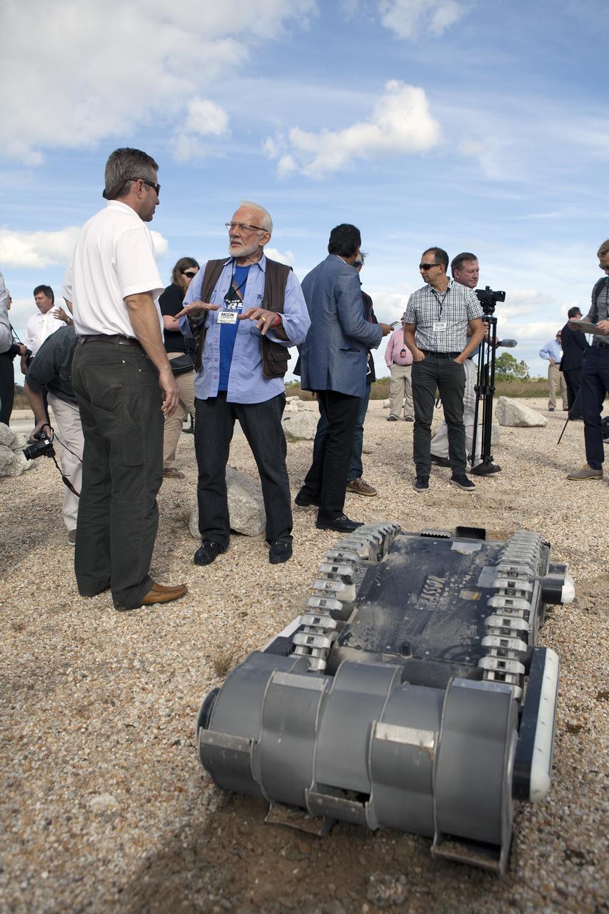 CAPE CANAVERAL, Fla. - Rob Mueller, left, NASA senior technologist in the Surface Systems Office in Kennedy Space Center's Engineering and Technology Directorate, talks with former NASA Apollo astronaut Buzz Aldrin during a demonstration of the Regolith Advanced Surface System Operations Robot, or RASSOR, at the automated landing and hazard avoidance technology, or ALHAT, hazard field at the north end of the Shuttle Landing Facility at NASA's Kennedy Space Center in Florida. The event was held to announce Moon Express Inc., of Moffett Field, California is selected to utilize Kennedy facilities for NASA's Lunar Cargo Transportation and Landing by Soft Touchdown, or Lunar CATALYST, initiative.     Moon Express is developing a lander with capabilities that will enable delivery of payloads to the surface of the moon, as well as new science and exploration missions of interest to  NASA and scientific and academic communities. Moon Express will base its activities at Kennedy and utilize the Morpheus ALHAT field and a hangar nearby for CATALYST testing. The Advanced Exploration Systems Division of NASA's Human Exploration and Operations Mission Directorate manages Lunar CATALYST. Photo credit: NASA/Ben Smegelsky
