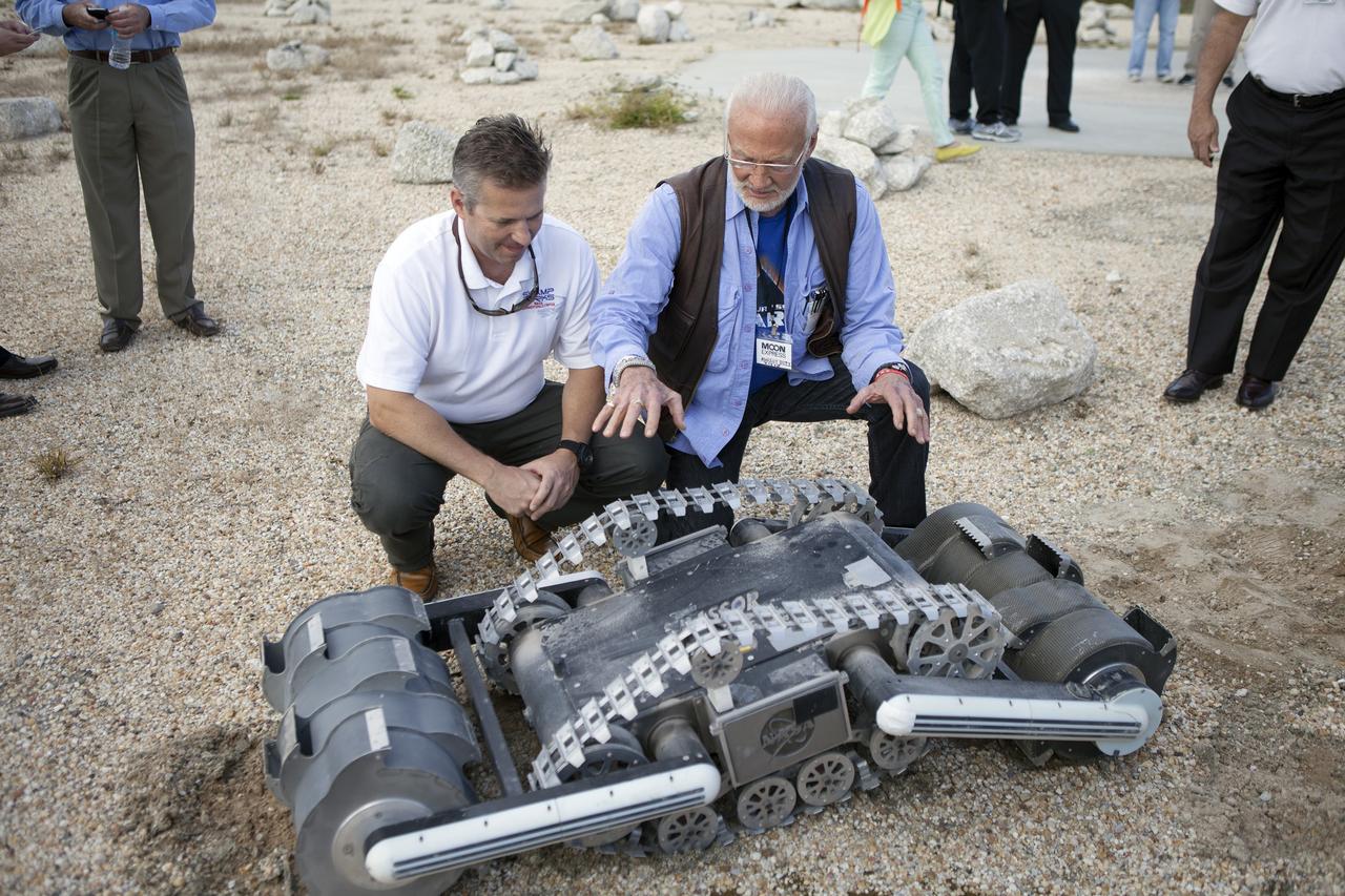 CAPE CANAVERAL, Fla. - Rob Mueller, left, NASA senior technologist in the Surface Systems Office in Kennedy Space Center's Engineering and Technology Directorate, talks with former NASA Apollo astronaut Buzz Aldrin during a demonstration of the Regolith Advanced Surface Systems Operations Robot, or RASSOR, at the automated landing and hazard avoidance technology, or ALHAT, hazard field at the north end of the Shuttle Landing Facility at NASA's Kennedy Space Center in Florida. The event was held to announce Moon Express Inc., of Moffett Field, California is selected to utilize Kennedy facilities for NASA's Lunar Cargo Transportation and Landing by Soft Touchdown, or Lunar CATALYST, initiative.     Moon Express is developing a lander with capabilities that will enable delivery of payloads to the surface of the moon, as well as new science and exploration missions of interest to  NASA and scientific and academic communities. Moon Express will base its activities at Kennedy and utilize the Morpheus ALHAT field and a hangar nearby for CATALYST testing. The Advanced Exploration Systems Division of NASA's Human Exploration and Operations Mission Directorate manages Lunar CATALYST. Photo credit: NASA/Ben Smegelsky
