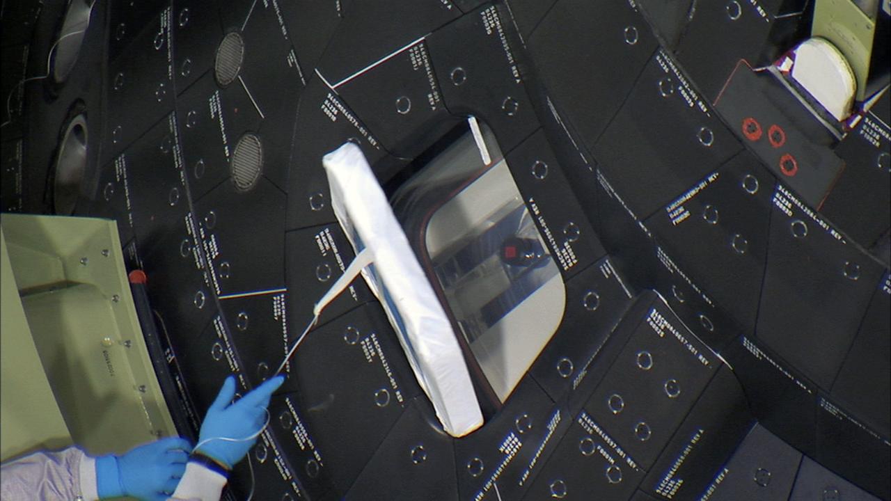 CAPE CANAVERAL, Fla. – Inside the Launch Abort System Facility at NASA's Kennedy Space Center in Florida, a technician carefully removes the window covers on Orion before the fourth and final Ogive panel is installed around the spacecraft and Launch Abort System. The Ogive panels will smooth the airflow over the conical spacecraft to limit sound and vibration, which will make for a much smoother ride for the astronauts who will ride inside Orion in the future. The work marked the final major assembly steps for the spacecraft before it is transported to Space Launch Complex 37 at Cape Canaveral Air Force Station in November. Orion is the exploration spacecraft designed to carry astronauts to destinations not yet explored by humans, including an asteroid and Mars. It will have emergency abort capability, sustain the crew during space travel and provide safe re-entry from deep space return velocities. The first unpiloted flight test of Orion is scheduled to launch in December 2014 atop a United Launch Alliance Delta IV Heavy rocket, and in 2018 on NASA’s Space Launch System rocket. For more information, visit www.nasa.gov/orion. Photo credit: Ben Smegelsky
