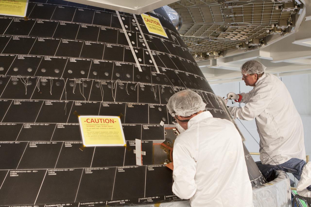 CAPE CANAVERAL, Fla. – Inside the Neil Armstrong Operations and Checkout Building high bay at NASA's Kennedy Space Center in Florida, Lockheed Martin technicians dressed in clean-room suits work on the back shell tile panels on the Orion crew module. Preparations are underway for Orion's first flight test. Orion is the exploration spacecraft designed to carry astronauts to destinations not yet explored by humans, including an asteroid and Mars. It will have emergency abort capability, sustain the crew during space travel and provide safe re-entry from deep space return velocities. Orion's first flight test is scheduled to launch in December atop a United Launch Alliance Delta IV Heavy rocket from Cape Canaveral Air Force Station in Florida to an altitude of 3,600 miles above the Earth's surface. The two-orbit, four-hour flight test will help engineers evaluate the systems critical to crew safety including the heat shield, parachute system and launch abort system. For more information, visit http://www.nasa.gov/orion. Photo credit: NASA/Gianni Woods