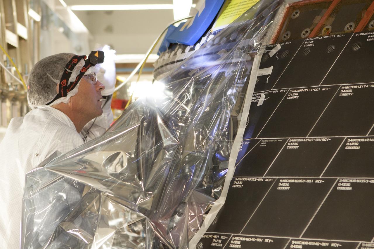 CAPE CANAVERAL, Fla. – Inside the Neil Armstrong Operations and Checkout Building high bay at NASA's Kennedy Space Center in Florida, a Lockheed Martin technician dressed in a clean room suit inspects the back shell tiles on the Orion crew module. Preparations are underway for Orion's first flight test. Orion is the exploration spacecraft designed to carry astronauts to destinations not yet explored by humans, including an asteroid and Mars. It will have emergency abort capability, sustain the crew during space travel and provide safe re-entry from deep space return velocities. Orion's first flight test is scheduled to launch in December atop a United Launch Alliance Delta IV Heavy rocket from Cape Canaveral Air Force Station in Florida to an altitude of 3,600 miles above the Earth's surface. The two-orbit, four-hour flight test will help engineers evaluate the systems critical to crew safety including the heat shield, parachute system and launch abort system. For more information, visit http://www.nasa.gov/orion. Photo credit: NASA/Gianni Woods