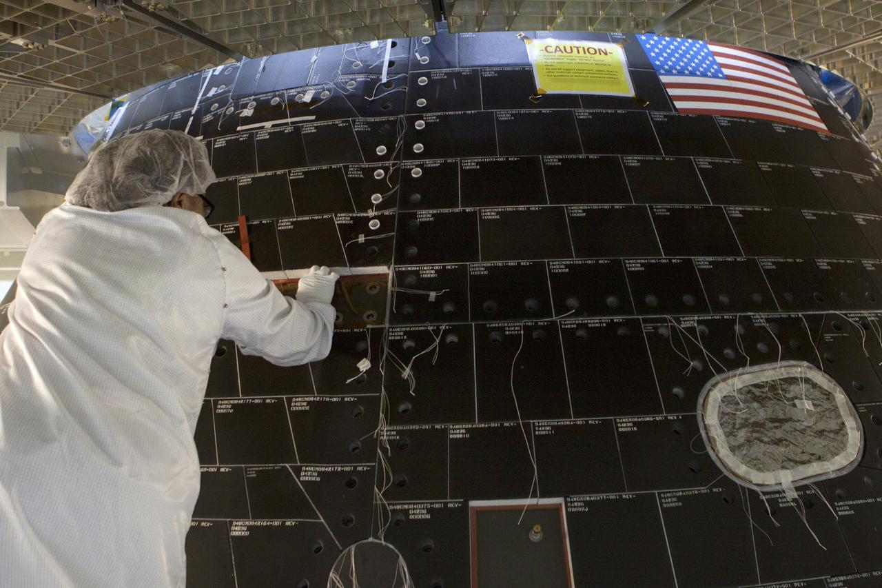 CAPE CANAVERAL, Fla. – Inside the Neil Armstrong Operations and Checkout Building high bay at NASA's Kennedy Space Center in Florida, a Lockheed Martin technician dressed in a clean room suit works on the back shell tile panels on the Orion crew module. Preparations are underway for Orion's first flight test. Orion is the exploration spacecraft designed to carry astronauts to destinations not yet explored by humans, including an asteroid and Mars. It will have emergency abort capability, sustain the crew during space travel and provide safe re-entry from deep space return velocities. Orion's first flight test is scheduled to launch in December atop a United Launch Alliance Delta IV Heavy rocket from Cape Canaveral Air Force Station in Florida to an altitude of 3,600 miles above the Earth's surface. The two-orbit, four-hour flight test will help engineers evaluate the systems critical to crew safety including the heat shield, parachute system and launch abort system. For more information, visit http://www.nasa.gov/orion. Photo credit: NASA/Gianni Woods