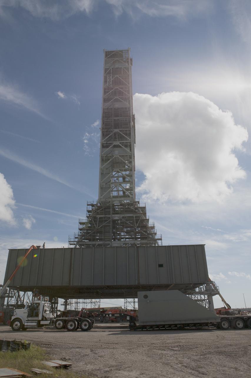 CAPE CANAVERAL, Fla. -- Modifications continue on the Mobile Launcher, or ML, at the Mobile Launcher Park Site at NASA’s Kennedy Space Center in Florida. The haunch, a structure that will support the launch vehicle on the ML, arrives by flatbed truck at the park site. The ML is being modified and strengthened to accommodate the weight, size and thrust at launch of NASA's Space Launch System, or SLS, and Orion spacecraft.    In 2013, the agency awarded a contract to J.P. Donovan Construction Inc. of Rockledge, Fla., to modify the ML, which is one of the key elements of ground support equipment that is being upgraded by the Ground Systems Development and Operations Program at Kennedy. The existing 24-foot exhaust hole is being enlarged and strengthened for the larger, heavier SLS rocket. The ML will carry the SLS rocket and Orion spacecraft to Launch Pad 39B for its first uncrewed mission, Exploration Mission-1, in 2018. Photo credit: NASA/Kim Shiflett