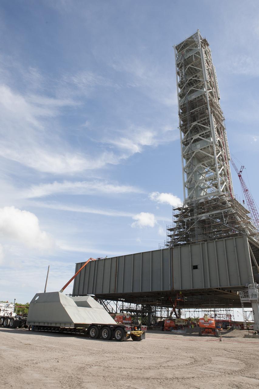 CAPE CANAVERAL, Fla. -- Modifications continue on the Mobile Launcher, or ML, at the Mobile Launcher Park Site at NASA’s Kennedy Space Center in Florida. The haunch, a structure that will support the launch vehicle on the ML, arrives by flatbed truck at the park site. The ML is being modified and strengthened to accommodate the weight, size and thrust at launch of NASA's Space Launch System, or SLS, and Orion spacecraft.    In 2013, the agency awarded a contract to J.P. Donovan Construction Inc. of Rockledge, Fla., to modify the ML, which is one of the key elements of ground support equipment that is being upgraded by the Ground Systems Development and Operations Program at Kennedy. The existing 24-foot exhaust hole is being enlarged and strengthened for the larger, heavier SLS rocket. The ML will carry the SLS rocket and Orion spacecraft to Launch Pad 39B for its first uncrewed mission, Exploration Mission-1, in 2018. Photo credit: NASA/Kim Shiflett