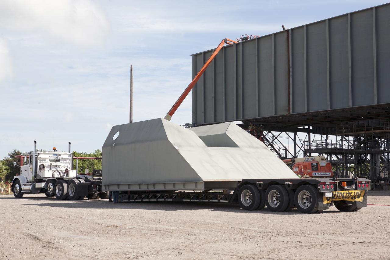 CAPE CANAVERAL, Fla. -- Modifications continue on the Mobile Launcher, or ML, at the Mobile Launcher Park Site at NASA’s Kennedy Space Center in Florida. The haunch, a structure that will support the launch vehicle on the ML, arrives by flatbed truck at the park site. The ML is being modified and strengthened to accommodate the weight, size and thrust at launch of NASA's Space Launch System, or SLS, and Orion spacecraft.    In 2013, the agency awarded a contract to J.P. Donovan Construction Inc. of Rockledge, Fla., to modify the ML, which is one of the key elements of ground support equipment that is being upgraded by the Ground Systems Development and Operations Program at Kennedy. The existing 24-foot exhaust hole is being enlarged and strengthened for the larger, heavier SLS rocket. The ML will carry the SLS rocket and Orion spacecraft to Launch Pad 39B for its first uncrewed mission, Exploration Mission-1, in 2018. Photo credit: NASA/Kim Shiflett
