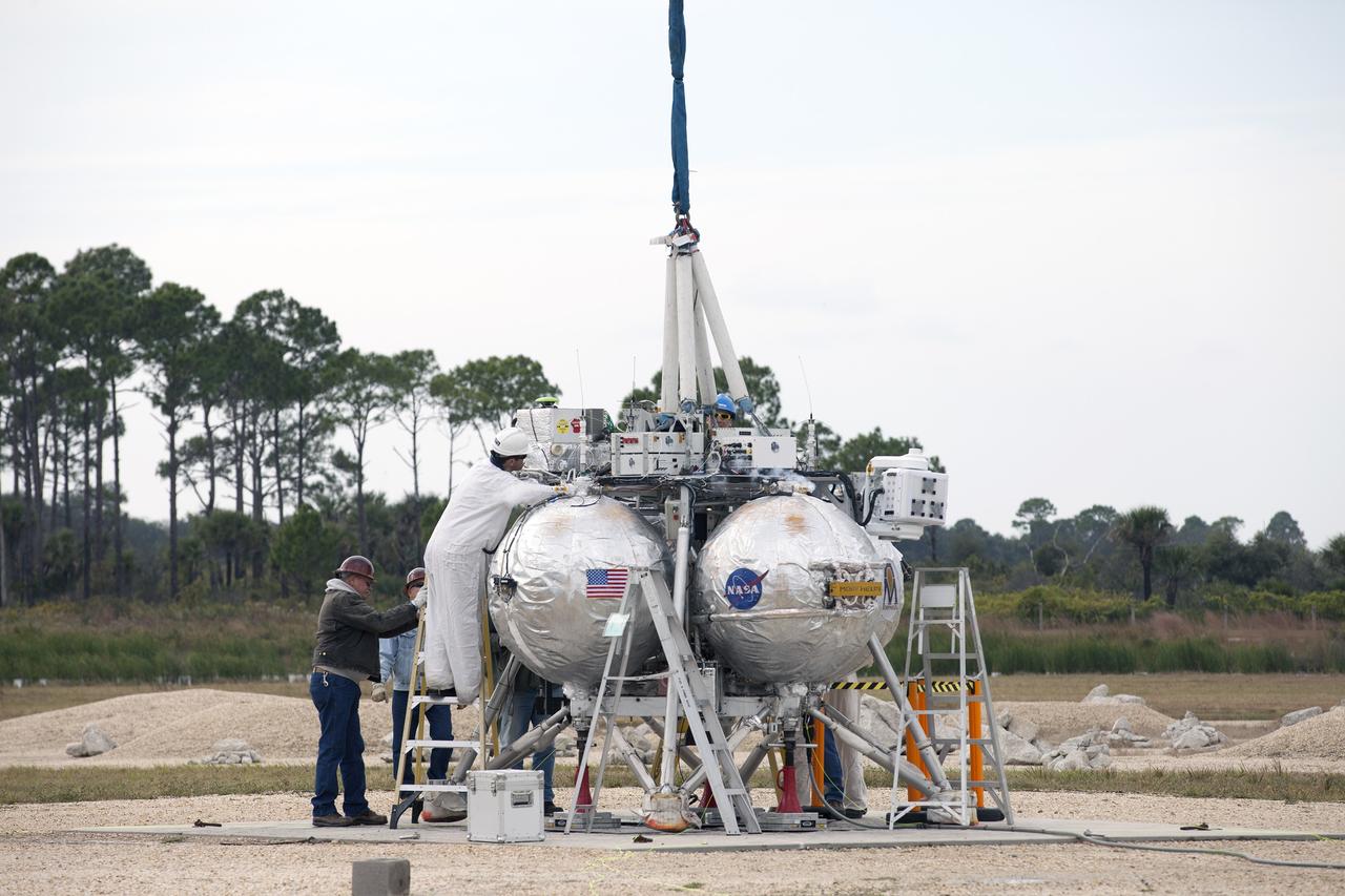 CAPE CANAVERAL, Fla. –NASA's Project Morpheus prototype lander undergoes final preparations for a tethered-flight test at the north end of the Shuttle Landing Facility at NASA’s Kennedy Space Center in Florida. For the 40-second test, the lander will be hoisted 20 feet. The spacecraft will ascend an additional five feet and hover for five seconds. Morpheus then will perform a 5.6-foot ascent coupled with a 9.8-foot traverse, and hover for five more seconds before returning to the launch point. A number of changes have been made, primarily focused on autonomous landing and hazard avoidance technology ALHAT and moving the Doppler Lidar to the front of the forward liquid oxygen tank.    The tether test was cut short due to Morpheus exceeding onboard abort rate limits. The vehicle was taken back to the hangar and data from the test is being studied. After review, managers will determine when a new test date will be set. The landing facility provides the lander with the kind of field necessary for realistic testing, complete with rocks, craters and hazards to avoid. Morpheus’ ALHAT payload allows it to navigate to clear landing sites amidst rocks, craters and other hazards during its descent. For more information on Project Morpheus, visit http://morpheuslander.jsc.nasa.gov/. Photo credit: NASA/Kim Shiflett