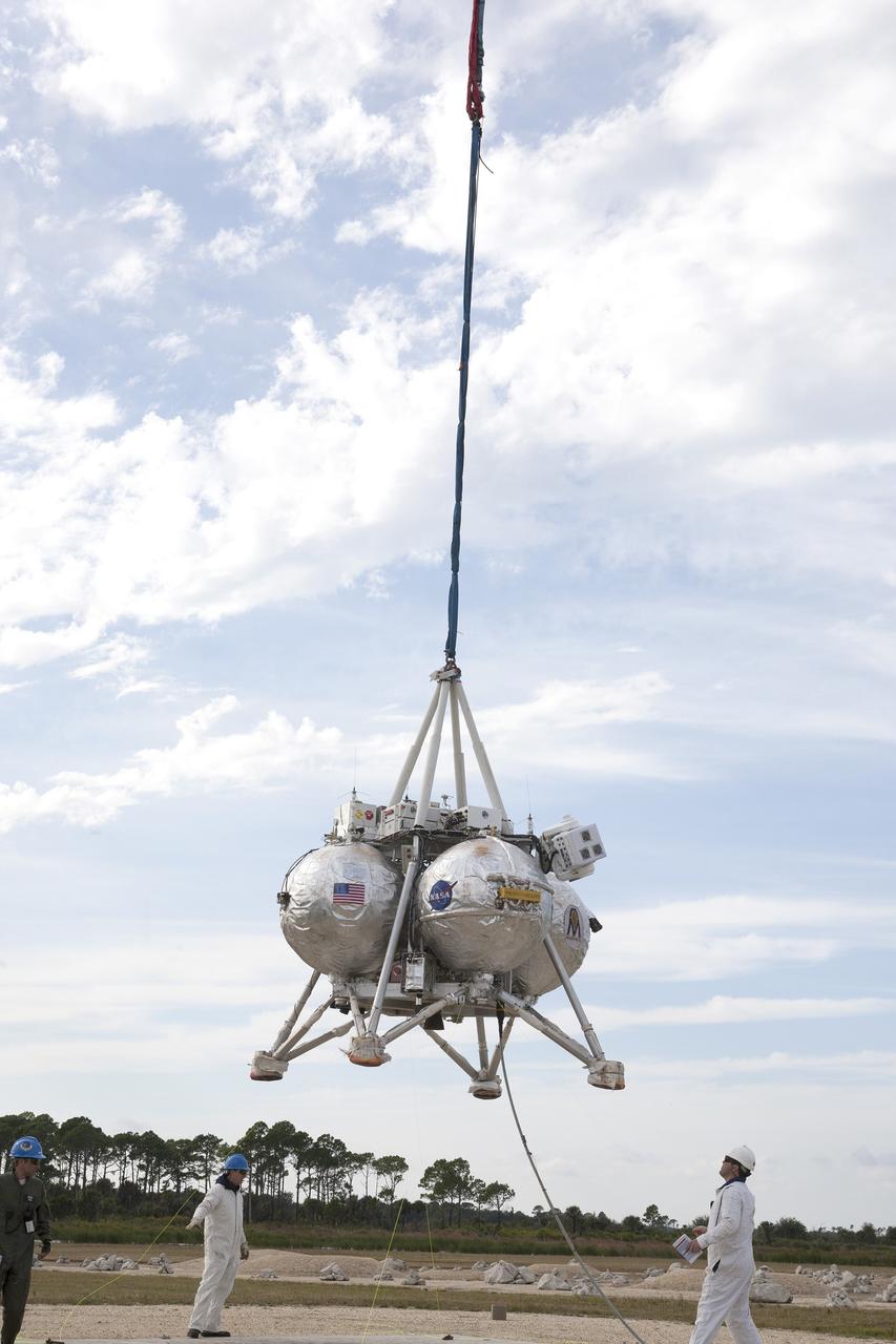 CAPE CANAVERAL, Fla. –NASA's Project Morpheus prototype lander is lifted by a crane in preparation for a tethered-flight test at the north end of the Shuttle Landing Facility at NASA’s Kennedy Space Center in Florida. For the 40-second test, the lander will be hoisted 20 feet. The spacecraft will ascend an additional five feet and hover for five seconds. Morpheus then will perform a 5.6-foot ascent coupled with a 9.8-foot traverse, and hover for five more seconds before returning to the launch point. A number of changes have been made, primarily focused on autonomous landing and hazard avoidance technology ALHAT and moving the Doppler Lidar to the front of the forward liquid oxygen tank.    The tether test was cut short due to Morpheus exceeding onboard abort rate limits. The vehicle was taken back to the hangar and data from the test is being studied. After review, managers will determine when a new test date will be set. The landing facility provides the lander with the kind of field necessary for realistic testing, complete with rocks, craters and hazards to avoid. Morpheus’ ALHAT payload allows it to navigate to clear landing sites amidst rocks, craters and other hazards during its descent. For more information on Project Morpheus, visit http://morpheuslander.jsc.nasa.gov/. Photo credit: NASA/Kim Shiflett