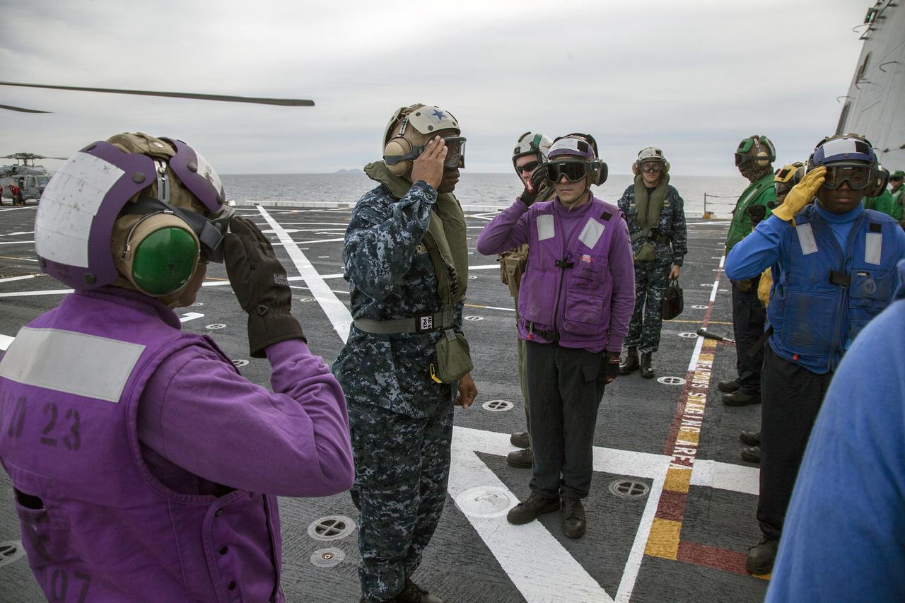 SAN DIEGO, Calif. – U.S. Navy and Helicopter Sea Combat Squadron 8 salute Rear Admiral Fernandez L. "Frank" Ponds, Commander, Expeditionary Strike Group 3, during his visit on the deck of the USS Anchorage near Naval Base San Diego in California. The ship is heading out to sea in the Pacific Ocean. NASA and the U.S. Navy are making preparations ahead of Orion's flight test for recovery of the crew module, forward bay cover and parachutes on its return from space and splashdown in the Pacific Ocean. The Ground Systems Development and Operations Program is leading the recovery efforts.    The first unpiloted flight test of Orion is scheduled to launch this week atop a United Launch Alliance Delta IV Heavy rocket. During its two-orbit, 4.5-hour flight, Orion will venture 3,600 miles in altitude and travel nearly 60,000 miles before returning to Earth for a splashdown in the Pacific Ocean. For more information, visit http://www.nasa.gov/orion. Photo credit: NASA/Cory Huston