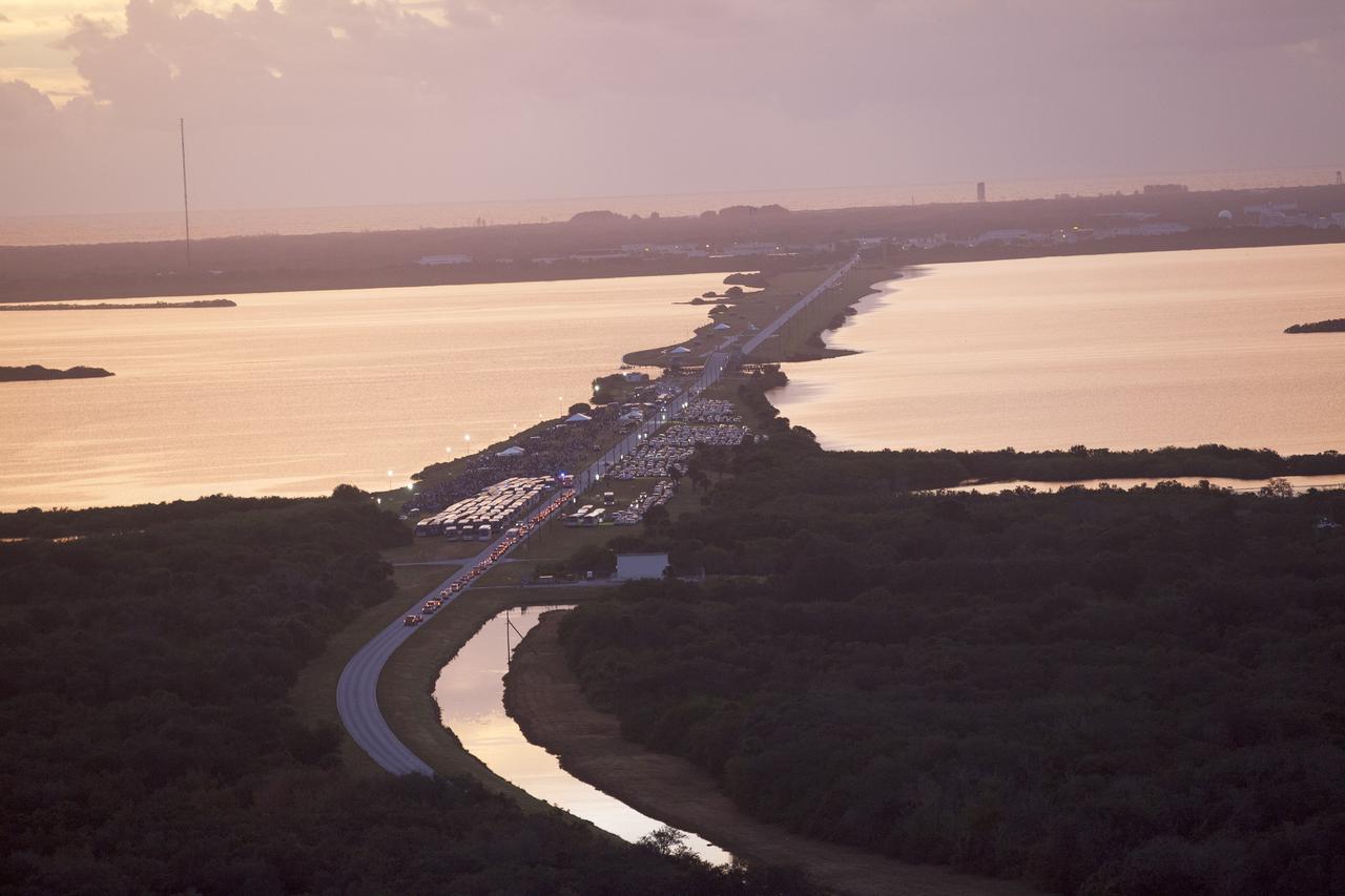 CAPE CANAVERAL, Fla. – This helicopter view of the NASA Causeway connecting NASA's Kennedy Space Center with Cape Canaveral Air Force Staton shows the thousands of vehicles parked where guests gather to see the launch of the Orion Flight Test. The liftoff was postponed because of an issue related to fill and drain valves on the Delta IV Heavy rocket that teams could not troubleshoot by the time the launch window expired. For more information, visit www.nasa.gov/orion Photo credit: NASA/Kim Shiflett