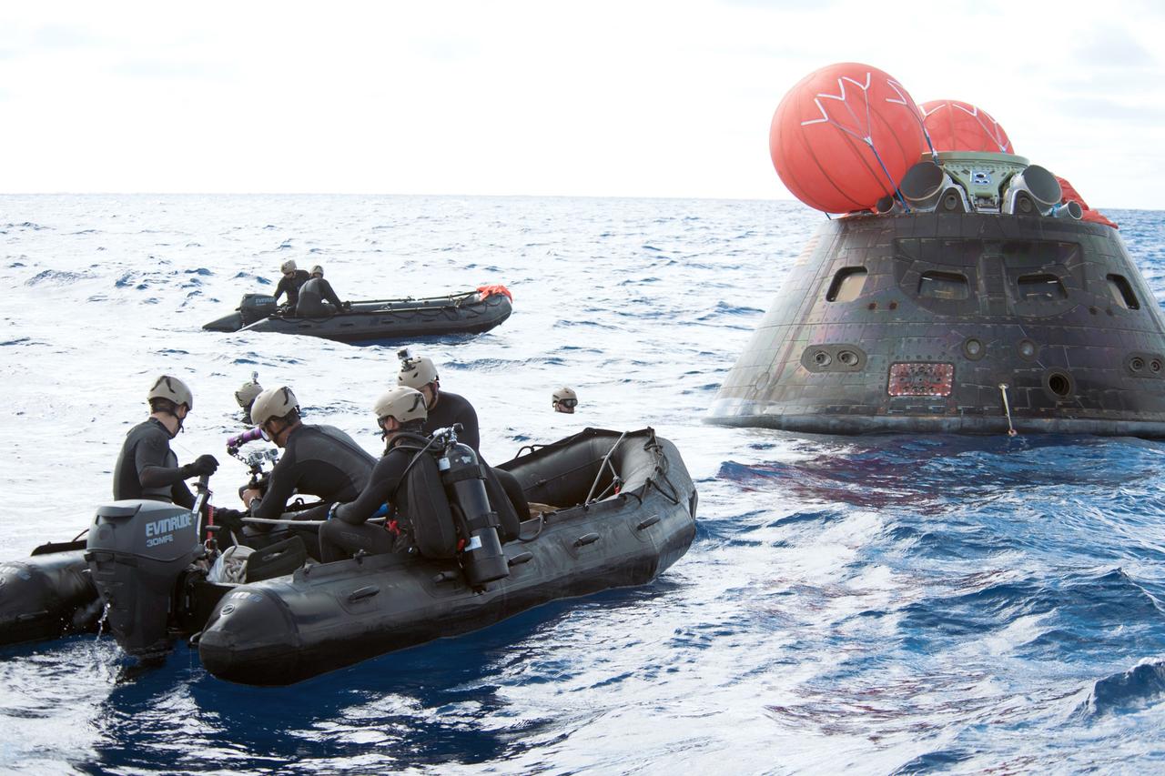 SAN DIEGO, Calif. -- NASA's Orion spacecraft splashed down in the Pacific Ocean after its first flight test atop a Delta IV Heavy rocket from Space Launch Complex 37 at Cape Canaveral Air Force Station in Florida. U.S. Navy divers in Zodiac boats prepare to recover Orion and tow her in to the well deck of the USS Anchorage. NASA's Orion spacecraft completed a two-orbit, four-and-a-half hour mission to test systems critical to crew safety, including the launch abort system, the heat shield and the parachute system. The Ground Systems Development and Operations Program is leading the recovery efforts. For more information, visit www.nasa.gov/orion Photo credit: Courtesy of U.S. Navy