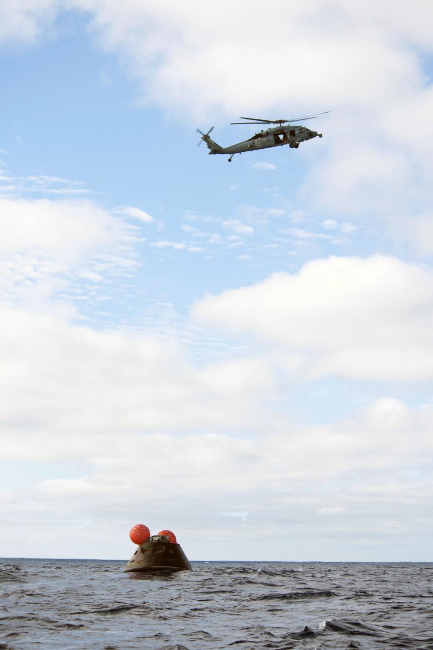 SAN DIEGO, Calif. -- NASA's Orion spacecraft floats in the Pacific Ocean after splashdown from its first flight test in Earth orbit. An H60-S Seahawk helicopter hovers above to communicate the spacecraft's location back to the USS Anchorage. NASA, the U.S. Navy and Lockheed Martin are coordinating efforts to recover Orion and secure the spacecraft in the well deck of the USS Anchorage. Orion completed a two-orbit, four-and-a-half hour mission, to test systems critical to crew safety, including the launch abort system, the heat shield and the parachute system. The Ground Systems Development and Operations Program is leading the recovery efforts. For more information, visit www.nasa.gov/orion Photo credit: NASA/Tony Gray