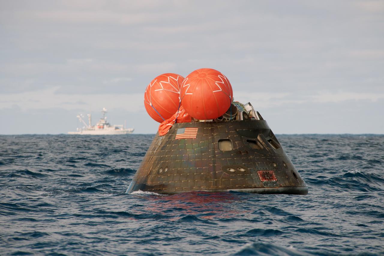 SAN DIEGO, Calif. -- NASA's Orion spacecraft floats in the Pacific Ocean after splashdown from its first flight test in Earth orbit. In the background is the USNS Salvor. This U.S. Navy salvage ship was there as a backup in case it was needed. NASA, the U.S. Navy and Lockheed Martin are coordinating efforts to recover Orion and secure the spacecraft in the well deck of the USS Anchorage. Orion completed a two-orbit, four-and-a-half hour mission, to test systems critical to crew safety, including the launch abort system, the heat shield and the parachute system. The Ground Systems Development and Operations Program is leading the recovery efforts. For more information, visit www.nasa.gov/orion Photo credit: NASA/Tony Gray