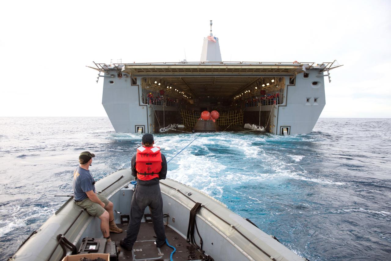 SAN DIEGO, Calif. -- U.S. Navy personnel aboard a rigid hull inflatable boat help recover NASA's Orion spacecraft following its splashdown in the Pacific Ocean after its first flight test in Earth orbit. Orion is towed into the flooded well deck of the USS Anchorage. NASA, the U.S. Navy and Lockheed Martin coordinated efforts to recover Orion, the forward bay cover and main parachutes. Orion completed a two-orbit, four-and-a-half hour mission, to test systems critical to crew safety, including the launch abort system, the heat shield and the parachute system. The Ground Systems Development and Operations Program is leading the recovery efforts. For more information, visit www.nasa.gov/orion Photo credit: NASA/Tony Gray
