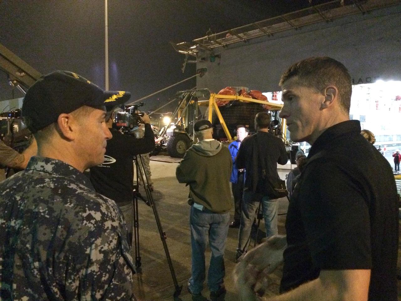 SAN DIEGO, Calif. -- At Naval Base San Diego in California, NASA Recovery Director Jeremy Graeber, right, talks to the commanding officer of the USS Anchorage as members of the news media prepare for viewing of NASA's Orion spacecraft being offloaded from the well deck of the ship. Orion has been secured in its crew module recovery cradle and will be prepared for return to Kennedy Space Center in Florida. After lifting off at 7:05 a.m. EST on Dec. 5 atop a Delta IV Heavy rocket from Space Launch Complex 37 at Cape Canaveral Air Force Station in Florida, Orion completed a two-orbit, four-and-a-half hour mission to test systems critical to crew safety, including the launch abort system, the heat shield and the parachute system. NASA, the U.S. Navy and Lockheed Martin coordinated efforts to recover Orion after splashdown in the Pacific Ocean. The Ground Systems Development and Operations Program is led the recovery efforts. For more information, visit www.nasa.gov/orion Photo credit: NASA/Amber Philman