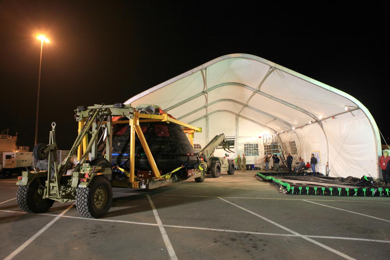 SAN DIEGO, Calif. -- The Orion crew module is being moved into a covered structure at the Mole Pier at Naval Base San Diego in California where it will be prepared for return to NASA's Kennedy Space Center in Florida. Orion was secured on its crew module recovery cradle in the well deck of the USS Anchorage after it was recovered from the Pacific Ocean. After lifting off at 7:05 a.m. EST on Dec. 5, atop a Delta IV Heavy rocket from Space Launch Complex 37 at Cape Canaveral Air Force Station in Florida, Orion completed a two-orbit, four-and-a-half hour mission to test systems critical to crew safety, including the launch abort system, the heat shield and the parachute system. NASA, the U.S. Navy and Lockheed Martin coordinated efforts to recover Orion after splashdown in the Pacific Ocean. The Ground Systems Development and Operations Program led the recovery efforts. For more information, visit www.nasa.gov/orion Photo credit: NASA/Cory Huston