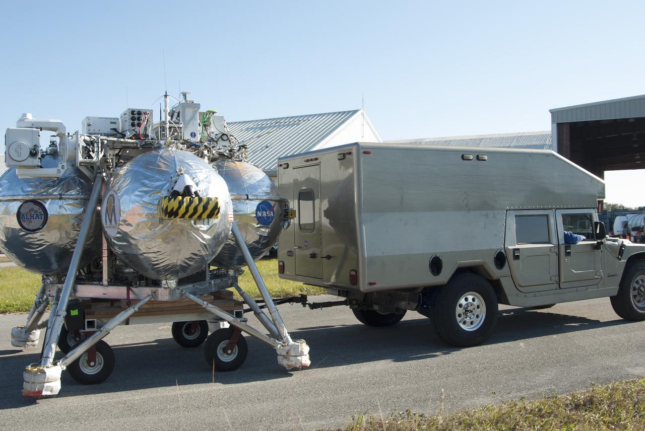 CAPE CANAVERAL, Fla. – NASA's Project Morpheus prototype lander is being transported from a hangar at the Shuttle Landing Facility, or SLF, for free flight test number 15 at the north end of the SLF at NASA’s Kennedy Space Center in Florida. The lander will take off from the ground over a flame trench and use its autonomous landing and hazard avoidance technology, or ALHAT sensors, to survey the hazard field to determine safe landing sites. Project Morpheus tests NASA’s ALHAT and an engine that runs on liquid oxygen and methane, which are green propellants. These new capabilities could be used in future efforts to deliver cargo to planetary surfaces. Project Morpheus is being managed under the Advanced Exploration Systems, or AES, Division in NASA’s Human Exploration and Operations Mission Directorate. For more information on Project Morpheus, visit http://morpheuslander.jsc.nasa.gov/.  Photo credit: NASA/Jim Grossmann