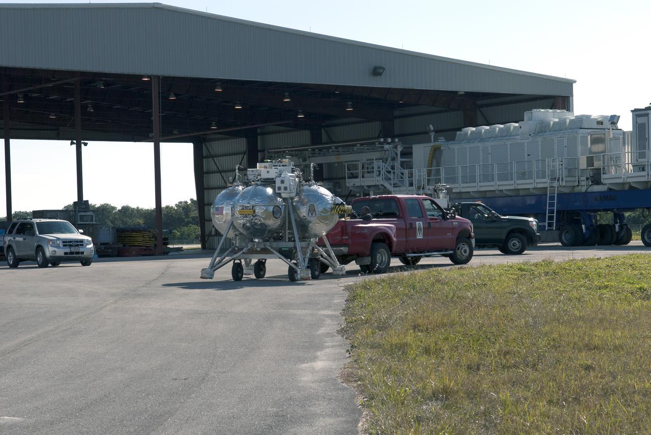 CAPE CANAVERAL, Fla. – NASA's Project Morpheus prototype lander is prepared for transport to the north end of the Shuttle Landing Facility for free flight test number 15 at NASA’s Kennedy Space Center in Florida. The lander will take off from the ground over a flame trench and use its autonomous landing and hazard avoidance technology, or ALHAT sensors, to survey the hazard field to determine safe landing sites. Project Morpheus tests NASA’s ALHAT and an engine that runs on liquid oxygen and methane, which are green propellants. These new capabilities could be used in future efforts to deliver cargo to planetary surfaces. Project Morpheus is being managed under the Advanced Exploration Systems, or AES, Division in NASA’s Human Exploration and Operations Mission Directorate. For more information on Project Morpheus, visit http://morpheuslander.jsc.nasa.gov/.  Photo credit: NASA/Jim Grossmann