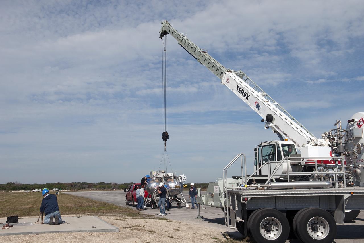 CAPE CANAVERAL, Fla. – NASA Project Morpheus prototype lander is being lifted by crane during preparations for free flight test number 15 at the north end of the Shuttle Landing Facility at NASA’s Kennedy Space Center in Florida. The lander will take off from the ground over a flame trench and use its autonomous landing and hazard avoidance technology, or ALHAT sensors, to survey the hazard field to determine safe landing sites. Project Morpheus tests NASA’s ALHAT and an engine that runs on liquid oxygen and methane, which are green propellants. These new capabilities could be used in future efforts to deliver cargo to planetary surfaces. Project Morpheus is being managed under the Advanced Exploration Systems, or AES, Division in NASA’s Human Exploration and Operations Mission Directorate. For more information on Project Morpheus, visit http://morpheuslander.jsc.nasa.gov/.  Photo credit: NASA/Jim Grossmann