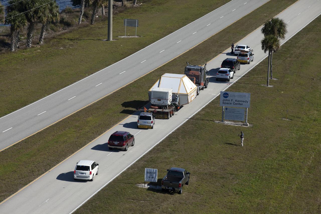 CAPE CANAVERAL, Fla. -- An aerial view near NASA's Kennedy Space Center Visitor Complex reveals the Orion crew module, enclosed in its crew module transportation fixture and secured on a flatbed truck that is proceeding onto the NASA Causeway that leads to the entrance gate to Kennedy Space Center in Florida. Orion made the 2,700 mile overland trip from Naval Base San Diego in California. The spacecraft was recovered from the Pacific Ocean after completing a two-orbit, four-and-a-half hour mission Dec. 5 to test systems critical to crew safety, including the launch abort system, the heat shield and the parachute system. The Ground Systems Development and Operations Program led the recovery, offload and transportation efforts. For more information, visit www.nasa.gov/orion. Photo credit: NASA/Kim Shiflett