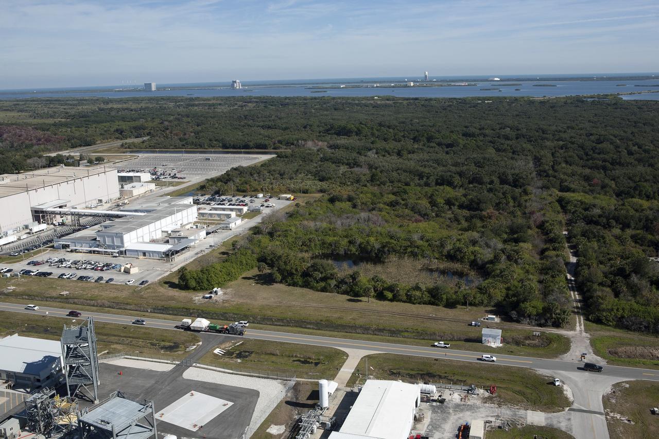 CAPE CANAVERAL, Fla. -- An aerial view reveals the Orion crew module, enclosed in its crew module transportation fixture and secured on a flatbed truck is passing the Space Station Processing Facility at Kennedy Space Center in Florida on its way to the Multi-Operation Support Building. Orion made the 2,700 mile overland trip from Naval Base San Diego in California. The spacecraft was recovered from the Pacific Ocean after completing a two-orbit, four-and-a-half hour mission Dec. 5 to test systems critical to crew safety, including the launch abort system, the heat shield and the parachute system. The Ground Systems Development and Operations Program led the recovery, offload and transportation efforts. For more information, visit www.nasa.gov/orion. Photo credit: NASA/Kim Shiflett