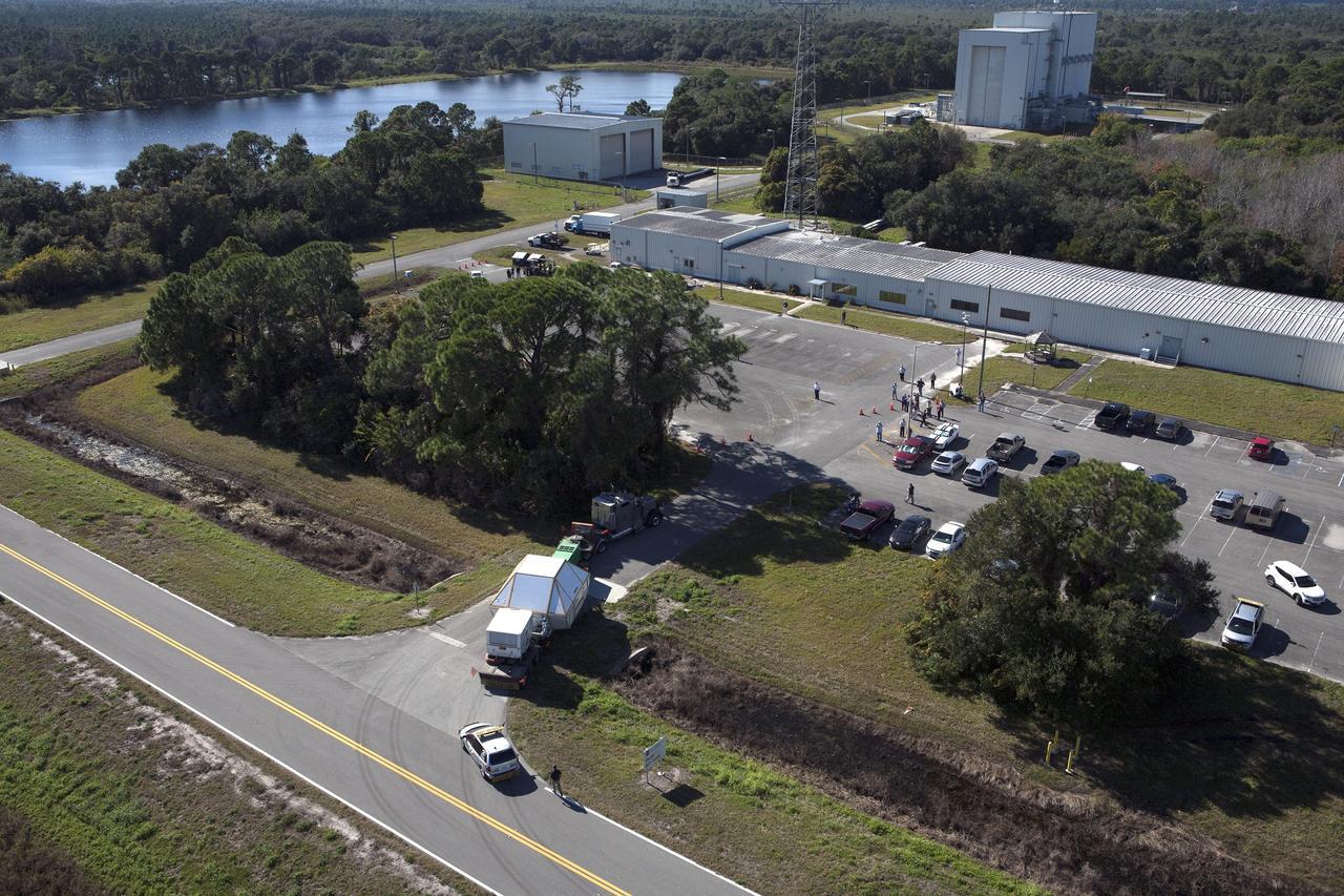 CAPE CANAVERAL, Fla. -- An aerial view reveals the Orion crew module, enclosed in its crew module transportation fixture and secured on a flatbed truck is proceeding to the Multi-Operation Support Building at NASA's Kennedy Space Center. Orion made the 2,700 mile overland trip from Naval Base San Diego in California. The spacecraft was recovered from the Pacific Ocean after completing a two-orbit, four-and-a-half hour mission Dec. 5 to test systems critical to crew safety, including the launch abort system, the heat shield and the parachute system. The Ground Systems Development and Operations Program led the recovery, offload and transportation efforts. For more information, visit www.nasa.gov/orion. Photo credit: NASA/Kim Shiflett