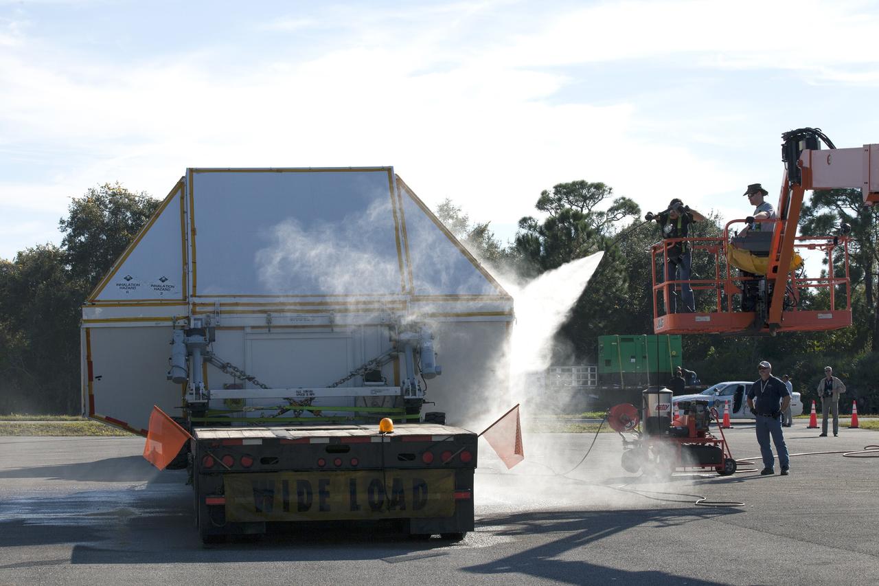 CAPE CANAVERAL, Fla. -- Technicians wash down the crew module transportation fixture containing the Orion crew module on the back of a flatbed truck at the Multi-Operation Support Building at NASA's Kennedy Space Center in Florida. Orion was transported 2,700 miles overland from Naval Base San Diego in California. Orion was recovered from the Pacific Ocean after completing a two-orbit, four-and-a-half hour mission Dec. 5 to test systems critical to crew safety, including the launch abort system, the heat shield and the parachute system. The Ground Systems Development and Operations Program led the recovery, offload and transportation efforts. For more information, visit www.nasa.gov/orion. Photo credit: NASA/Kim Shiflett