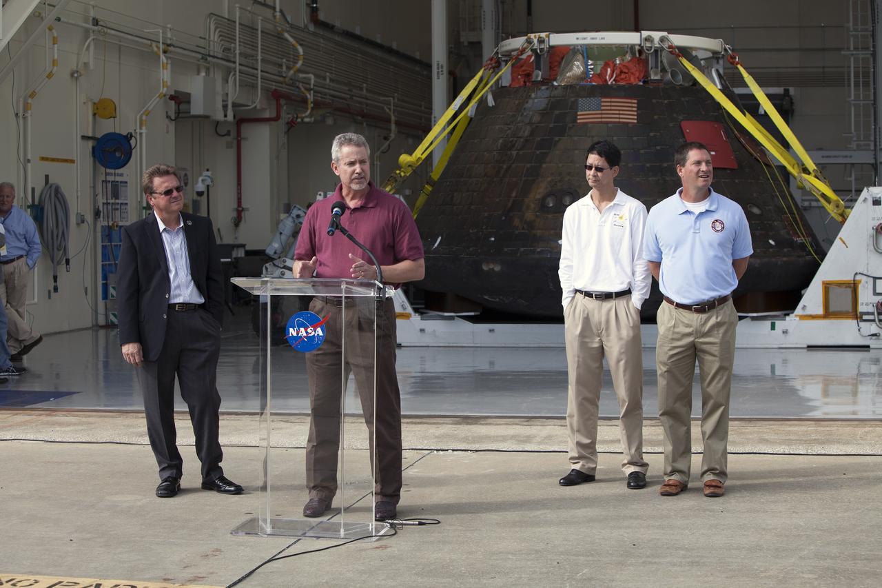 CAPE CANAVERAL, Fla. -- NASA's Orion spacecraft is viewed by members of the media at the Launch Abort System Facility at NASA's Kennedy Space Center in Florida. Speaking to the media during the viewing opportunity is Phil Weber, with the Ground Systems Development and Operations Program, or GSDO. At left is Jules Schneider, Lockheed Martin manager. At right is Glenn Chin, Orion Production Operations, and Lou Garcia, with GSDO. Orion made the 8-day, 2,700 mile overland trip back to Kennedy from Naval Base San Diego in California.  Analysis of date obtained during its two-orbit, four-and-a-half hour mission Dec. 5 will provide engineers detailed information on how the spacecraft fared. GSDO led the recovery, offload and transportation efforts. For more information, visit www.nasa.gov/orion. Photo credit: NASA/Dimitri Gerondidakis