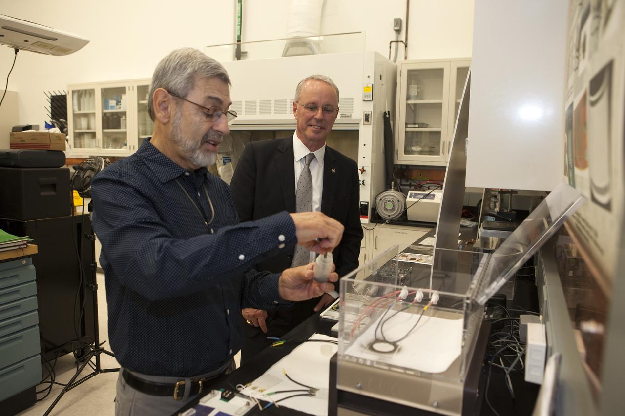 CAPE CANAVERAL, Fla. -- During a visit to NASA's Kennedy Space Center in Florida, NASA Chief Technologist David Miller, right, tours laboratories inside the Swamp Works facility. At left, Dr. Carlos Calle, lead in the Electrostatics and Surface Physics Laboratory, demonstrates a system that uses an electric field wave to move simulated moon dust away from surfaces. Photo credit: NASA/Kim Shiflett