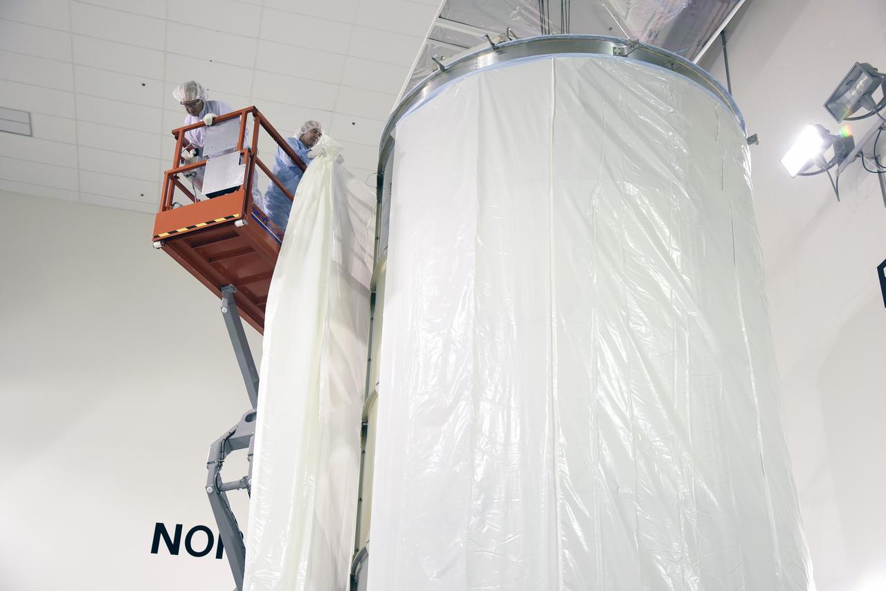 VANDENBERG AIR FORCE BASE, Calif. – In the Astrotech payload processing facility on Vandenberg Air Force Base in California, technicians enclose a transportation canister containing NASA's Soil Moisture Active Passive, or SMAP, spacecraft in an environmentally protective wrap for its move to the launch pad.    SMAP will launch on a United Launch Alliance Delta II 7320 configuration vehicle featuring a United Launch Alliance first stage booster powered by an Aerojet Rocketdyne RS-27A main engine and three Alliant Techsystems, or ATK, strap-on solid rocket motors. Once on station in Earth orbit, SMAP will provide global measurements of soil moisture and its freeze/thaw state. These measurements will be used to enhance understanding of processes that link the water, energy and carbon cycles, and to extend the capabilities of weather and climate prediction models. SMAP data also will be used to quantify net carbon flux in boreal landscapes and to develop improved flood prediction and drought monitoring capabilities. Launch from Space Launch Complex 2 is targeted for Jan. 29. To learn more about SMAP, visit http://www.nasa.gov/smap.  Photo credit: NASA/U.S. Air Force Photo Squadron