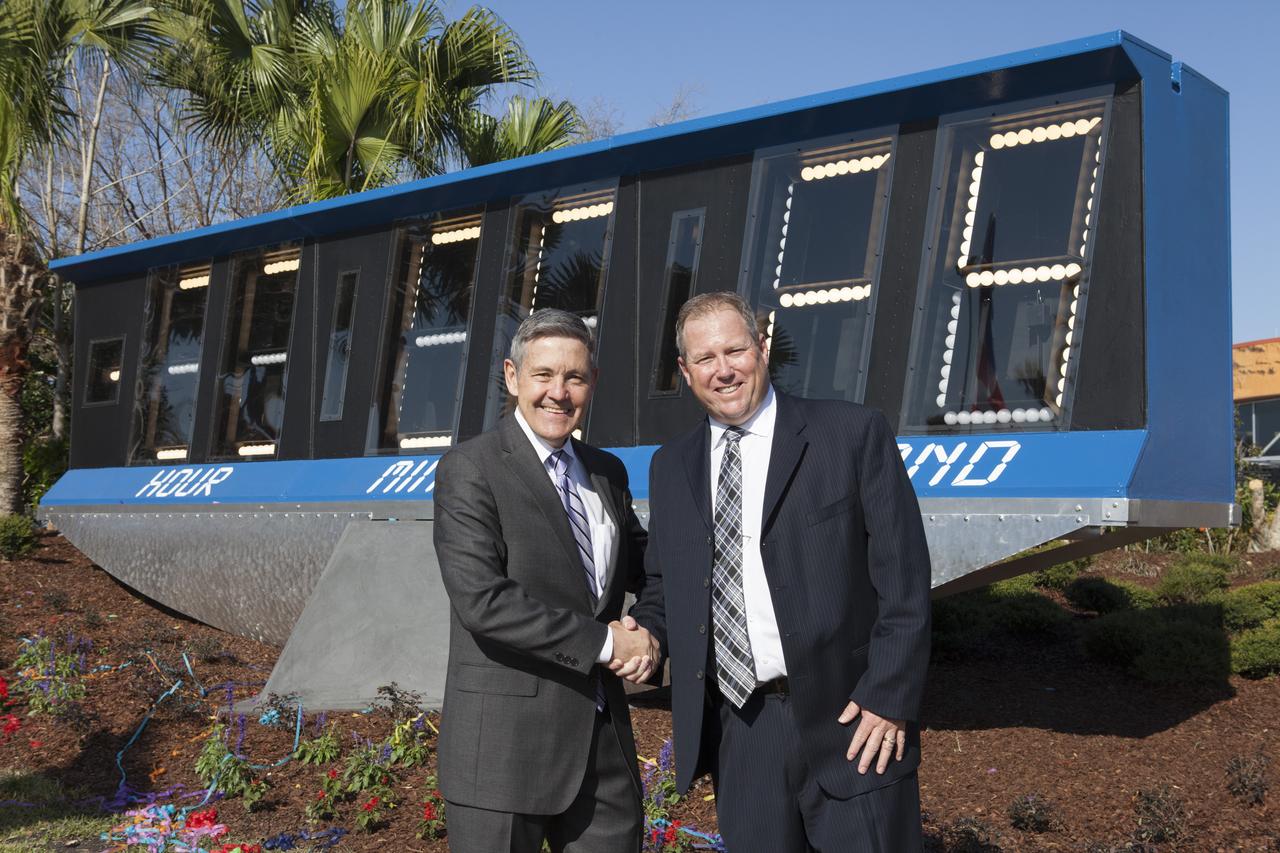 Kennedy Space Center Director Bob Cabana, left, and Therrin Protze, chief operating officer of Kennedy's Visitor Complex, celebrate the dedication of the spaceport's historic countdown clock as the newest display at the center's visitor complex. Now located at the entrance to the visitor complex, the spaceport's historic countdown clock was used starting with the launch of Apollo 12 on Nov. 14, 1969. Originally set up at the space center's Press Site, the clock operated through the final space shuttle mission, STS-135, launched on July 8, 2011. The old countdown clock was replaced in 2014 with a modern light emitting diode, or LED, display.