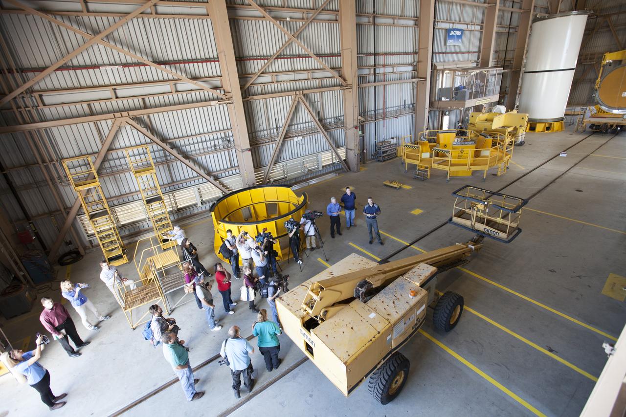 Members of the news media view the high bay inside the Rotation, Processing and Surge Facility (RPSF) at NASA’s Kennedy Space Center in Florida. Inside the RPSF, engineers and technicians with Jacobs Engineering on the Test and Operations Support Contract, explain the various test stands. In the far corner is one of two pathfinders, or test versions, of solid rocket booster segments for NASA’s Space Launch System rocket. The Ground Systems Development and Operations Program and Jacobs are preparing the booster segments, which are inert, for a series of lifts, moves and stacking operations to prepare for Exploration Mission-1, deep-space missions and the journey to Mars.
