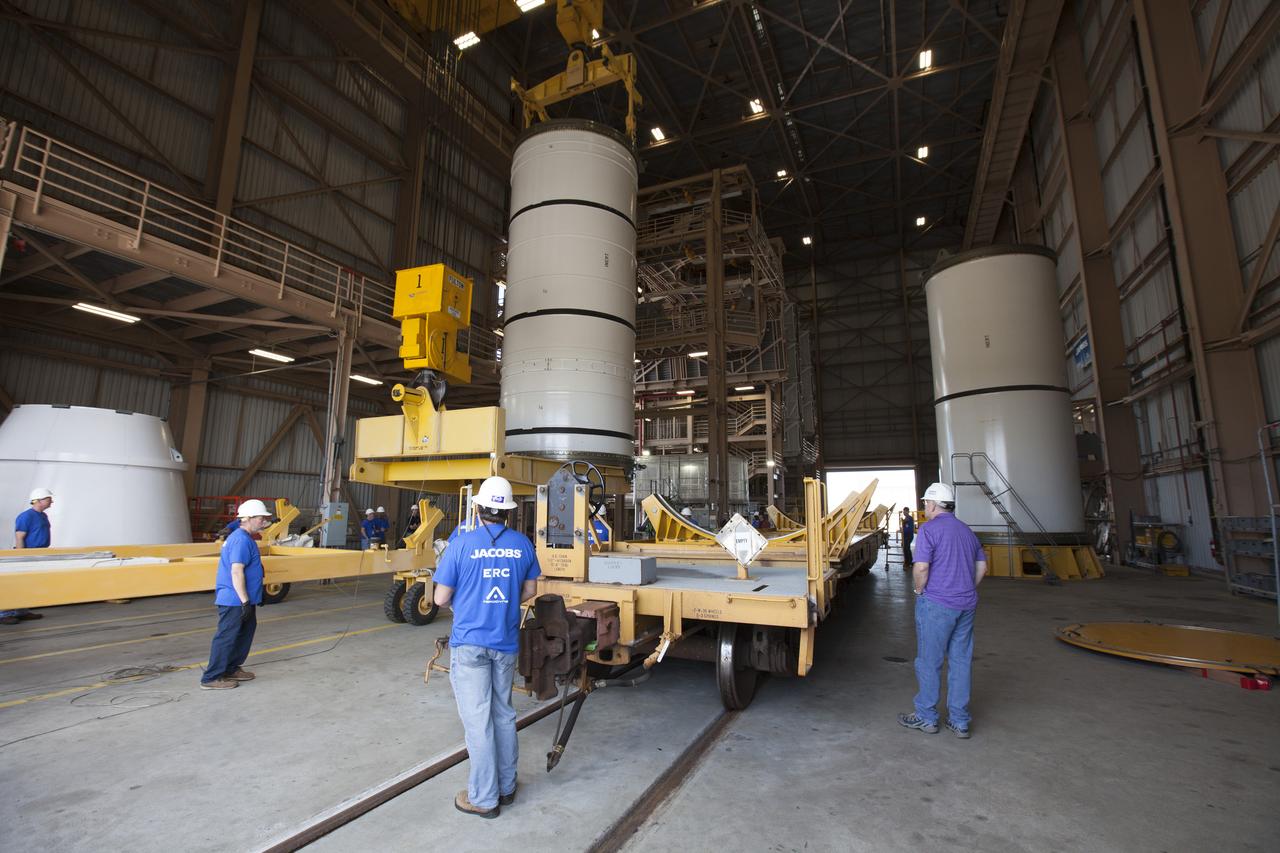 Engineers and technicians with Jacobs Engineering on the Test and Operations Contract monitor the progress as a crane is used to move one of two pathfinders, or test versions, of solid rocket booster segments for NASA’s Space Launch System (SLS) rocket. At far right, the first pathfinder booster segment has been secured in the vertical position on a test stand. Inside the RPSF, the Ground Systems Development and Operations Program and Jacobs will prepare the booster segments, which are inert, for a series of lifts, moves and stacking operations to prepare for Exploration Mission-1, deep-space missions and the journey to Mars. 