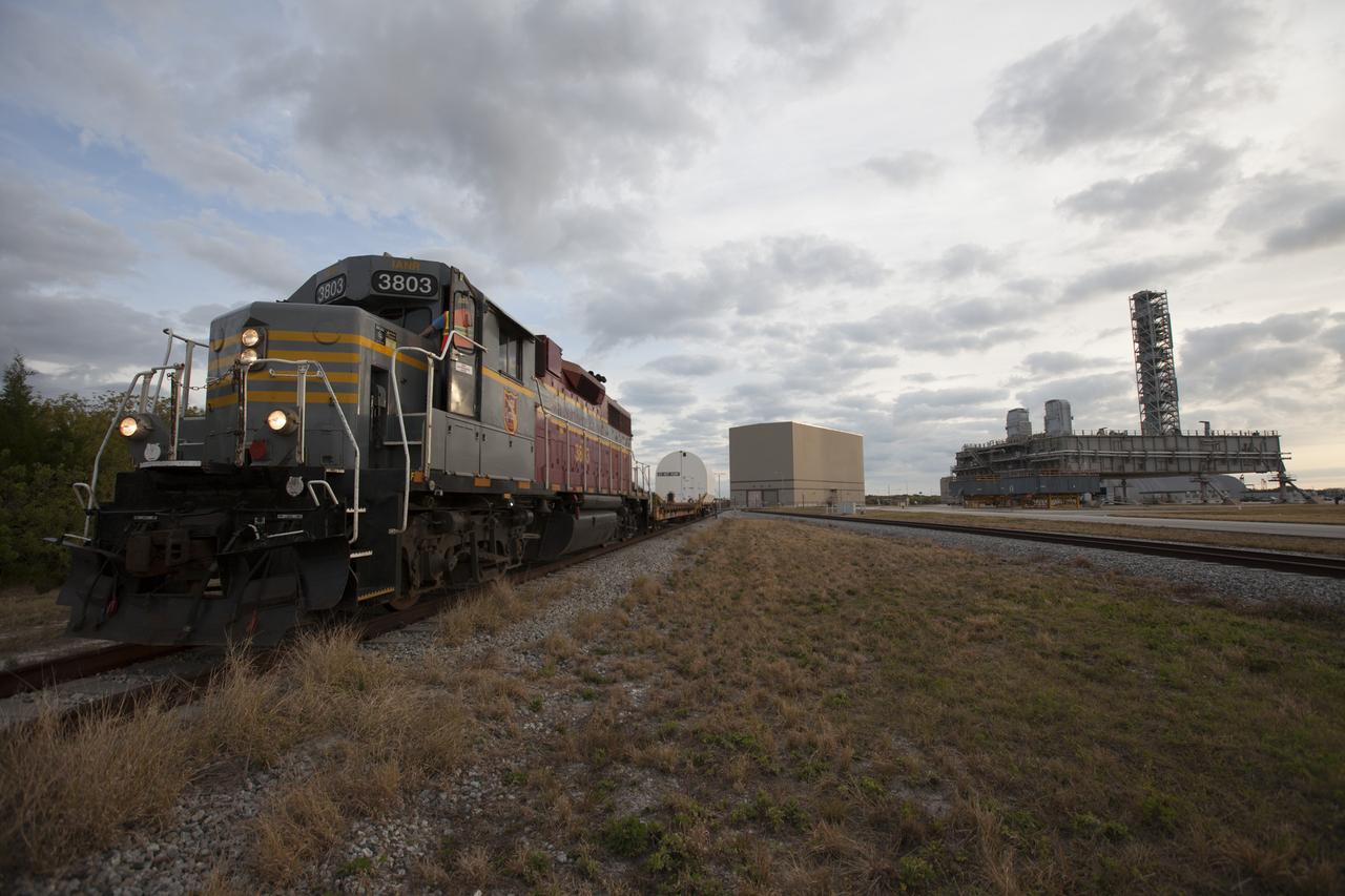 An Iowa Northern locomotive, contracted by Goodloe Transportation of Chicago, departs from NASA’s Kennedy Space Center in Florida, with two containers on railcars for transport to the Jay Jay railroad yard. The containers held two pathfinders, or test versions, of solid rocket booster segments for NASA’s Space Launch System rocket that were delivered to the Rotation, Processing and Surge Facility (RPSF). Inside the RPSF, the Ground Systems Development and Operations Program and Jacobs Engineering, on the Test and Operations Support Contract, will conduct a series of lifts, moves and stacking operations using the booster segments, which are inert, to prepare for Exploration Mission-1, deep-space missions and the journey to Mars. The pathfinder booster segments are from Orbital ATK in Utah.